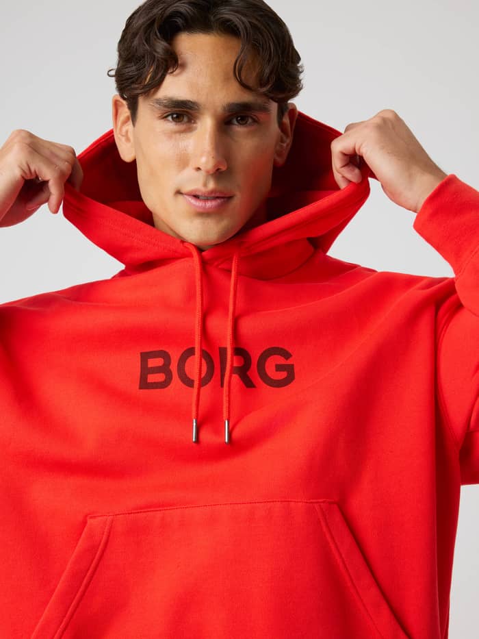 Front view of a man in the Borg Oversized Hoodie in Flame Scarlet (Red) with a black logo for training and tennis. - Image 5