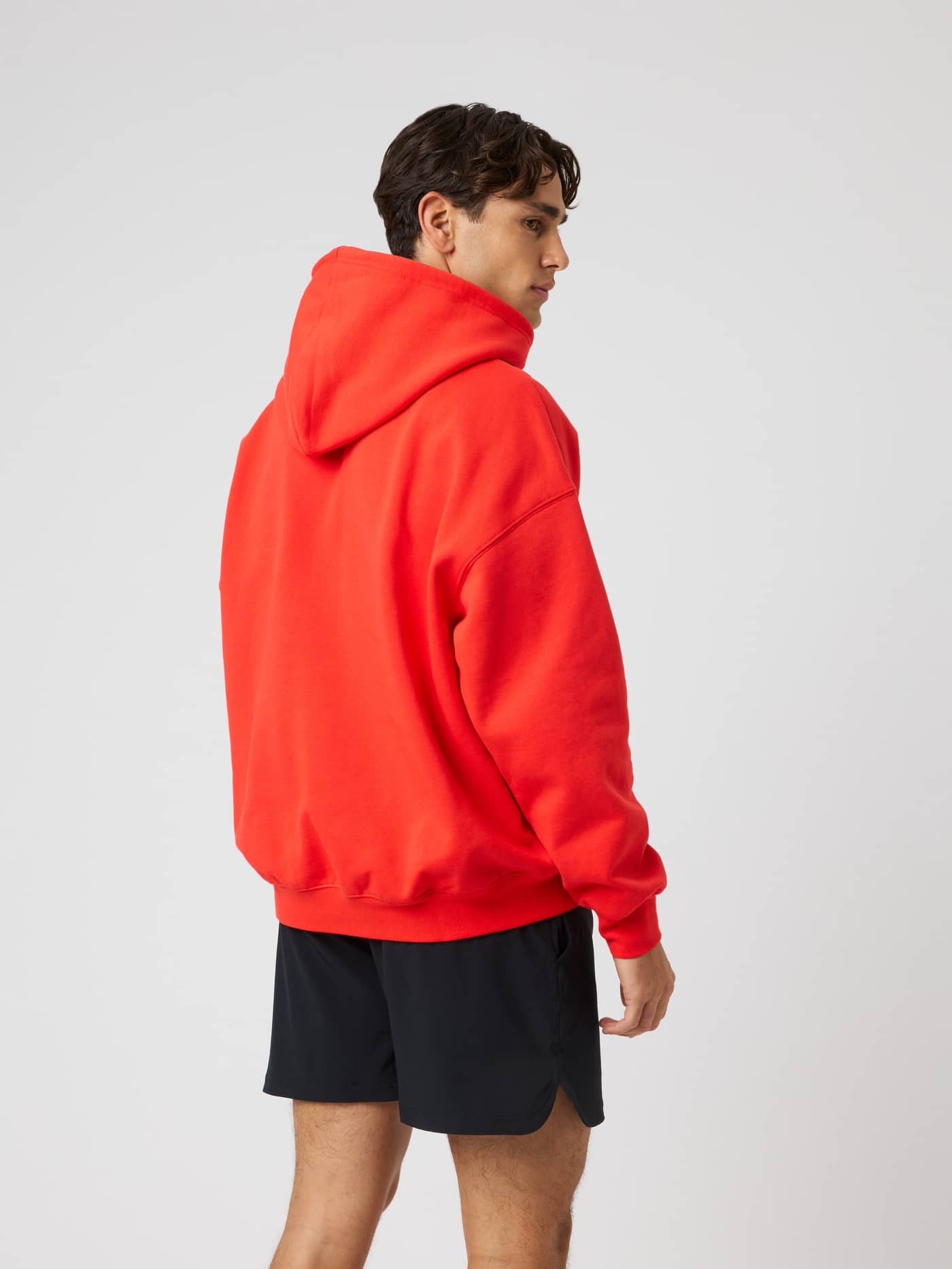 Three-quarter back view of a model in the Borg Oversized Hoodie in Flame Scarlet (Red) for training and warm-ups. - Image 3