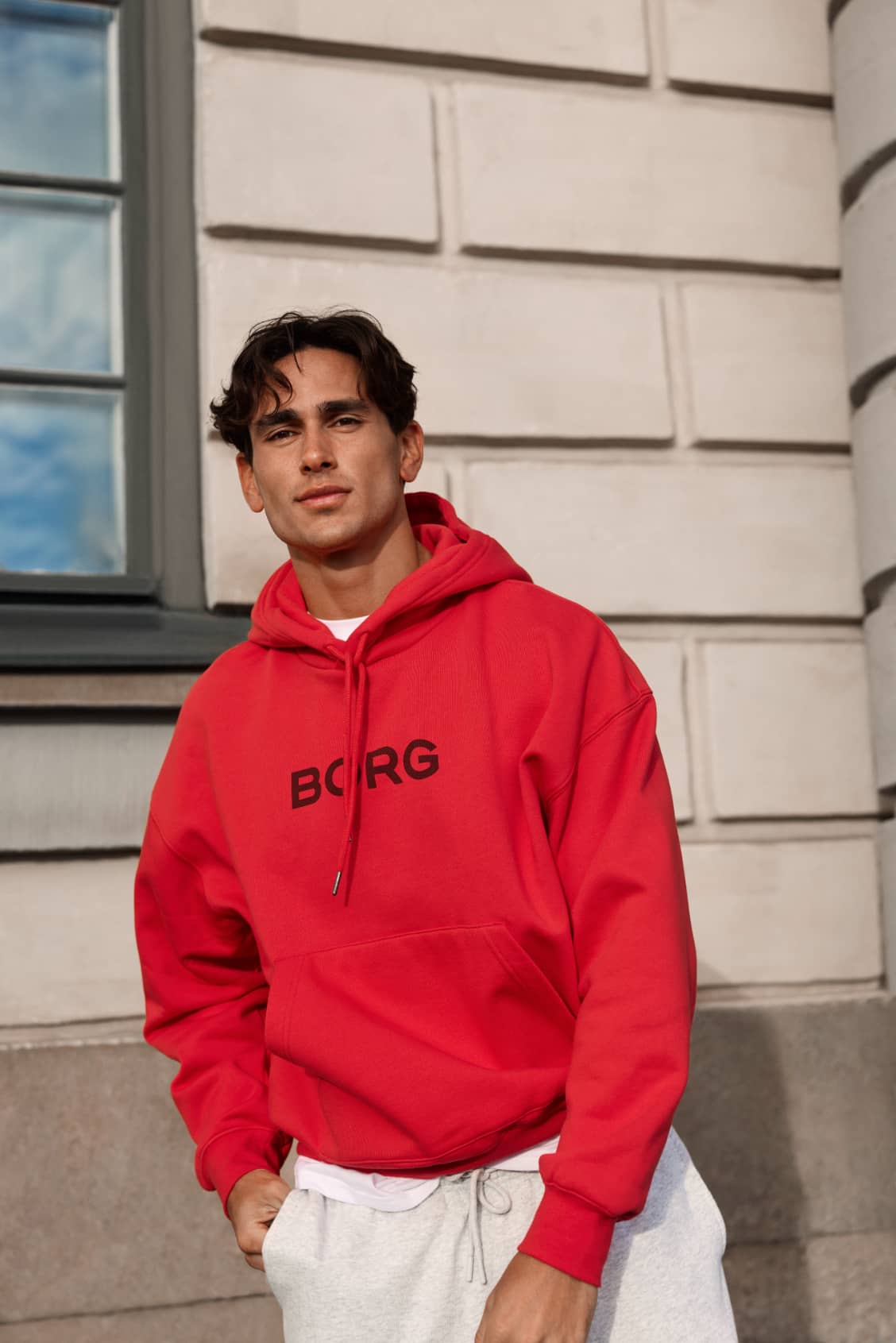 Front view of a man wearing the Borg Oversized Hoodie in Flame Scarlet (red) with a chest graphic and relaxed fit. - Image 1