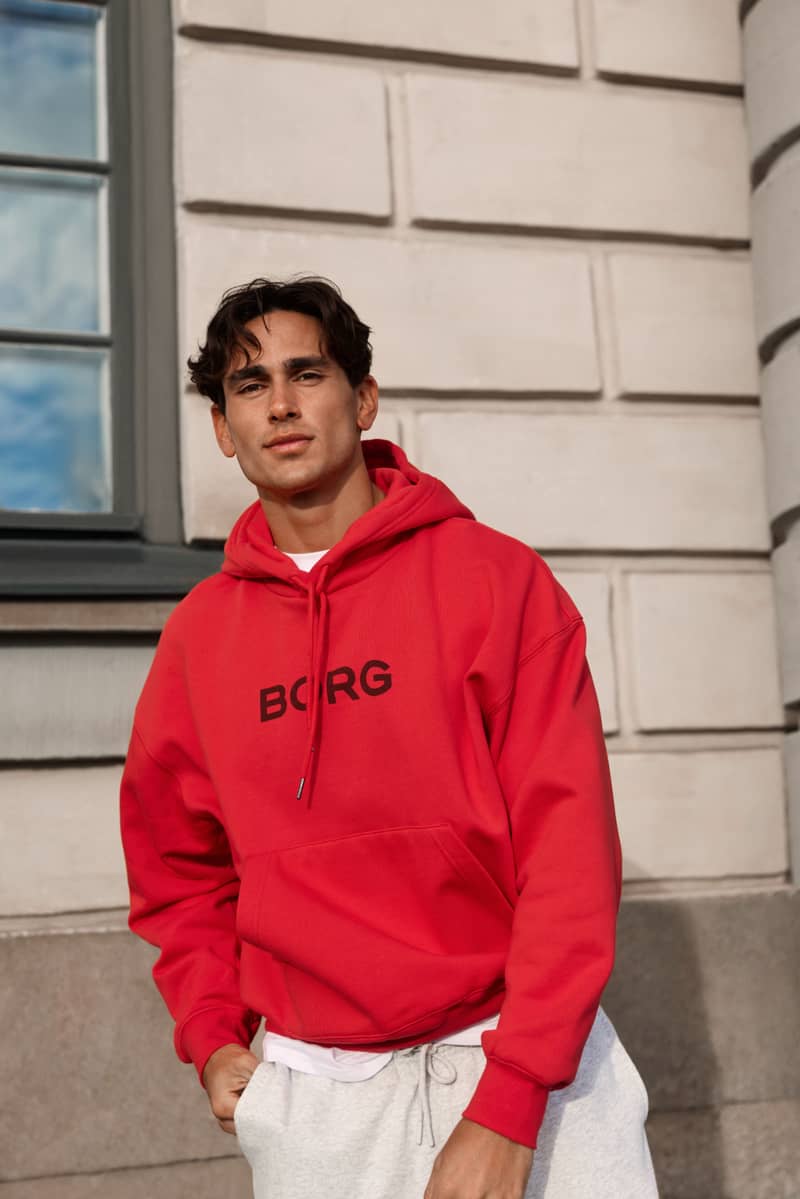 Front view of a man wearing the Borg Oversized Hoodie in Flame Scarlet (red) with a chest graphic and relaxed fit.