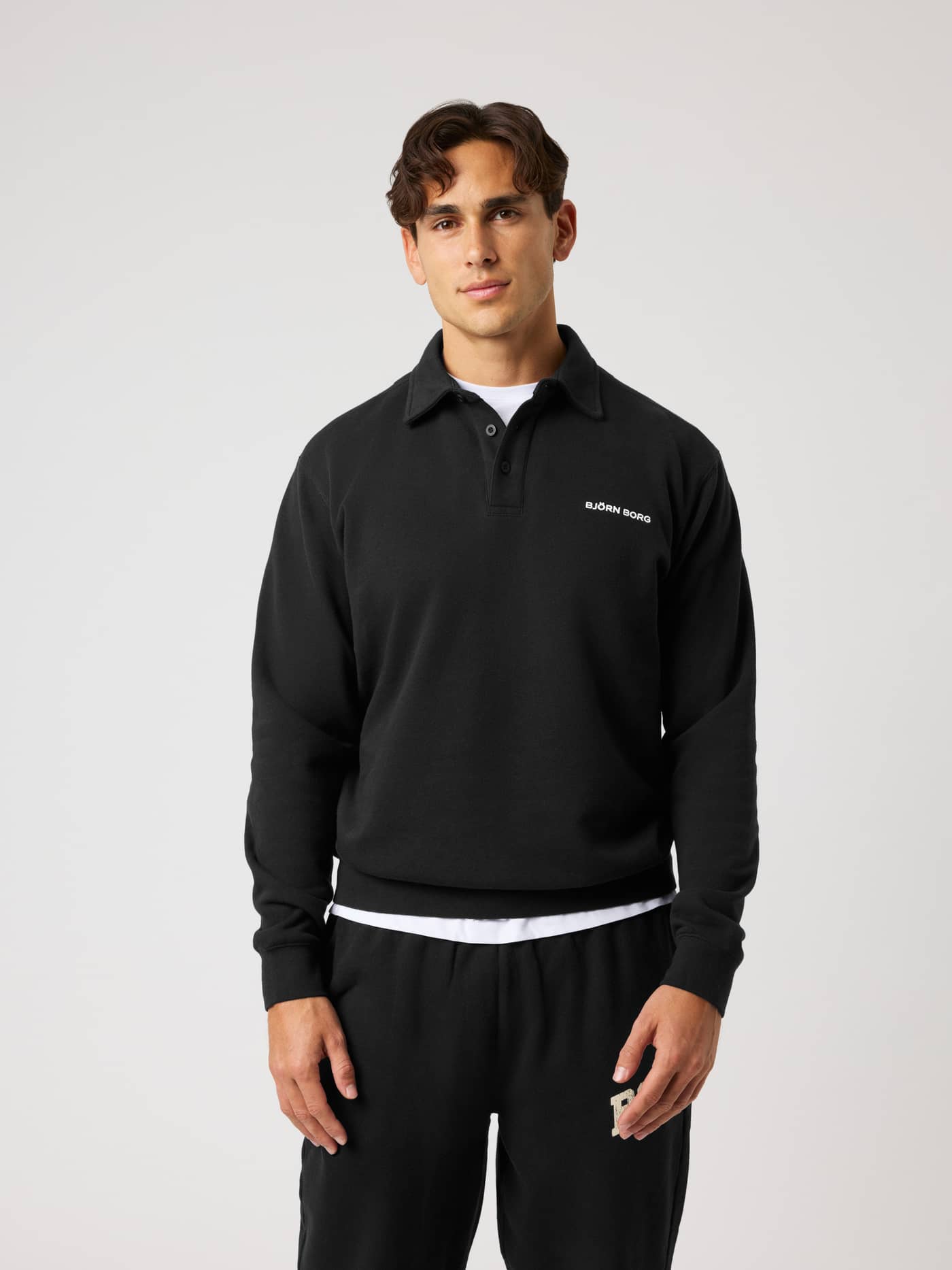 Vue de face d'un homme en Borg Classic Polo Sweatshirt en Black Beauty (Noir) avec logo blanc pour le tennis et le training. - Image 1
