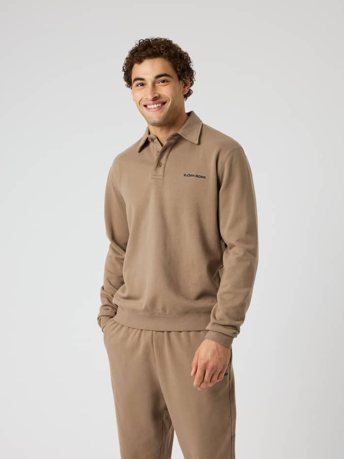 Front view of a man in the Borg Classic Polo Sweatshirt in Caribou (Brown) with a black logo for tennis and training.