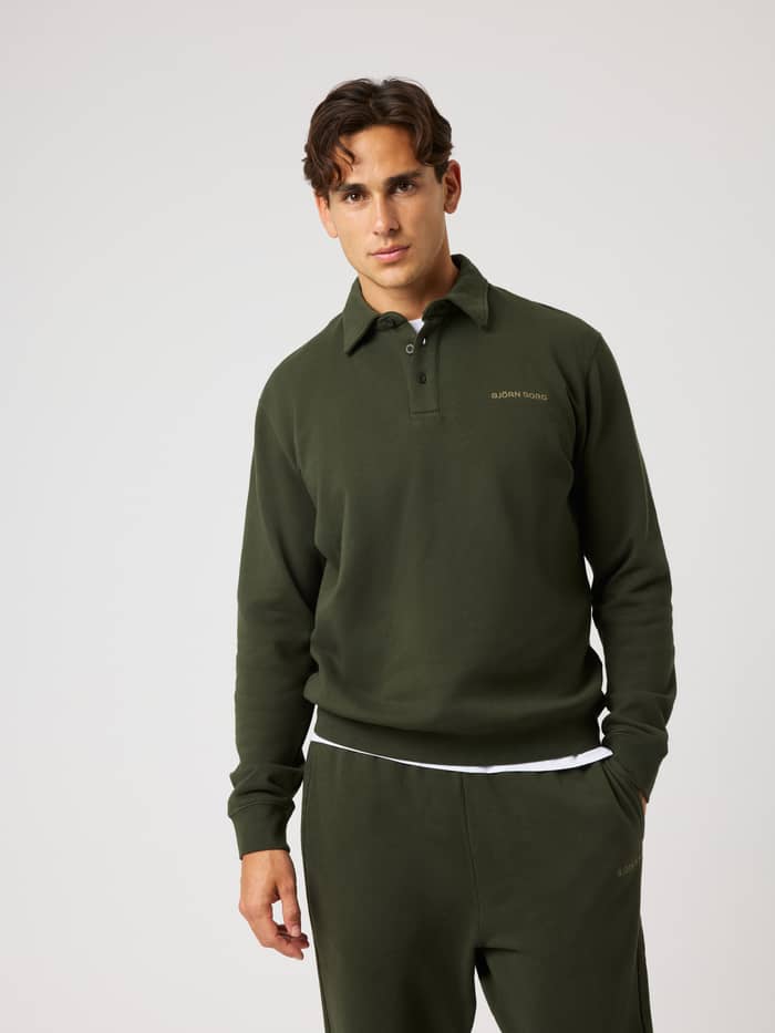 Front view of a man in the cotton Borg Classic Polo Sweatshirt in Rosin (Green) with a tan chest logo for light training.