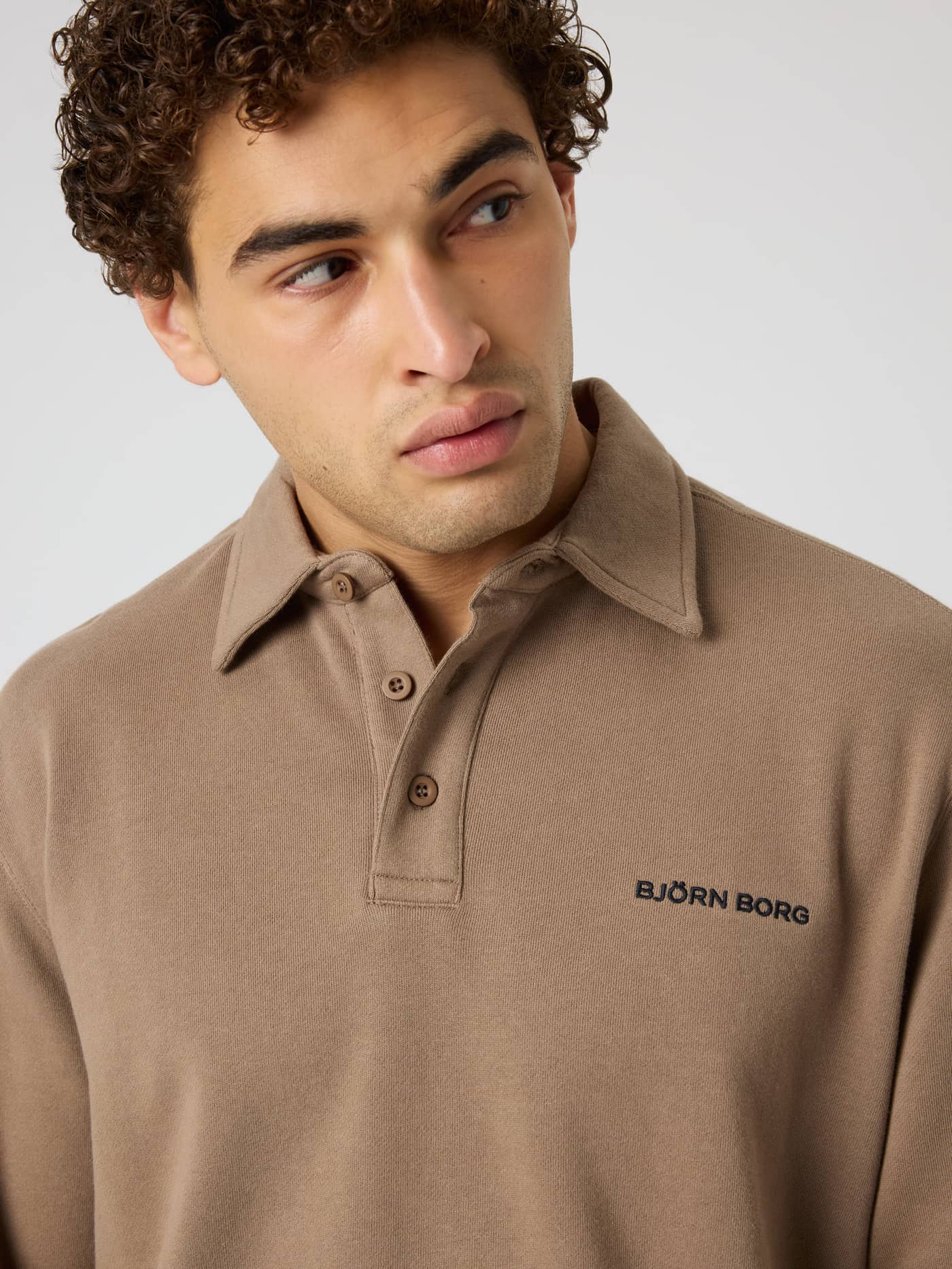 Close-up of the Borg Classic Polo Sweatshirt in Caribou (Brown) with a button placket and black logo for tennis and training. - Image 5