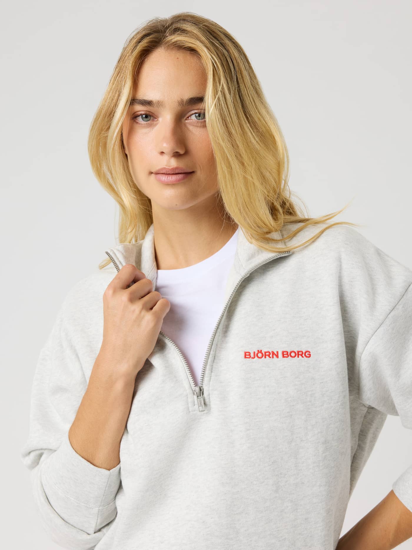 Close-up of the Borg Halfzip Sweatshirt in Ultra Light Grey Melange (Grey) with a red logo and a premium half-zip collar. - Image 5