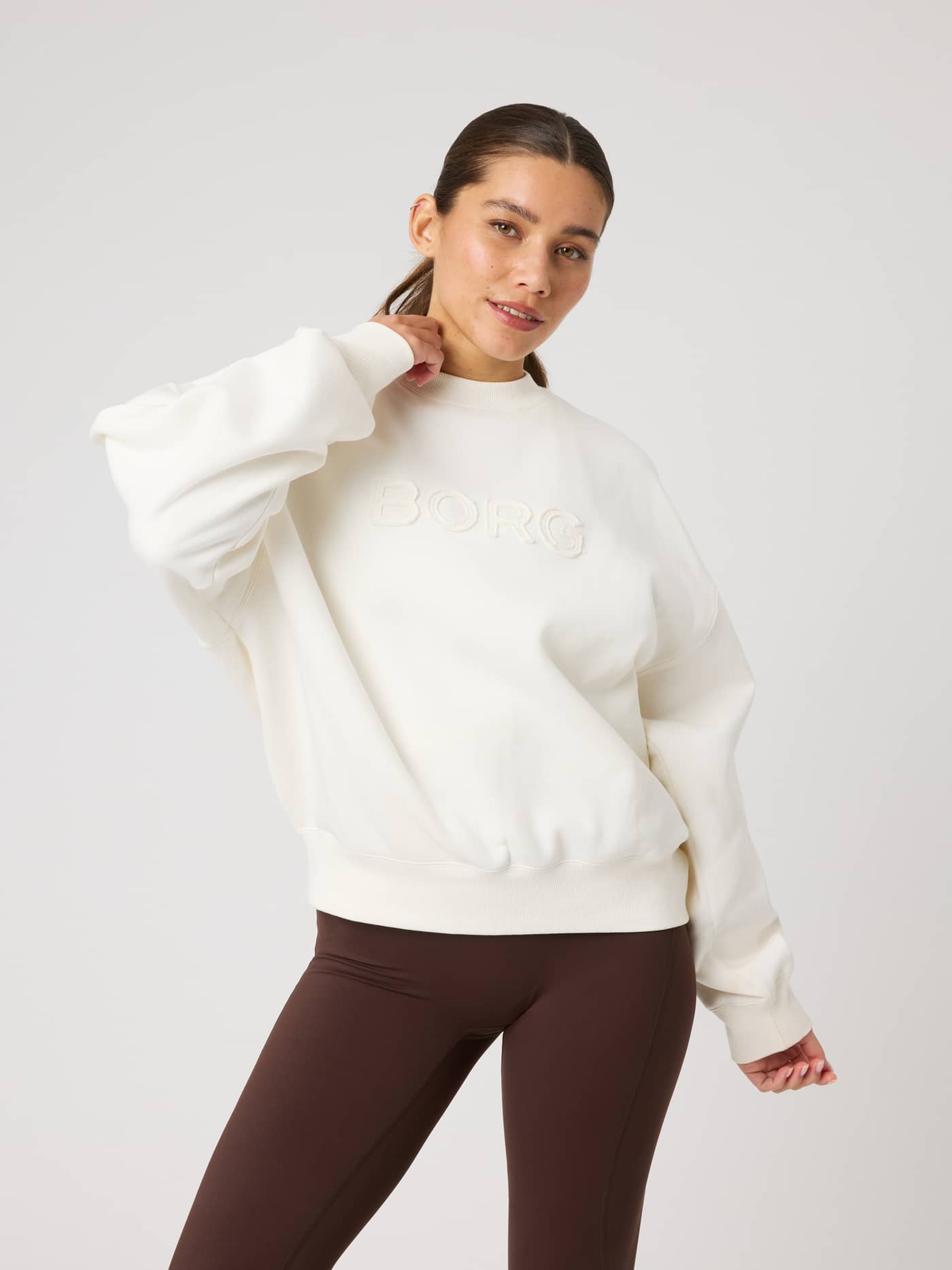 Front view of a model wearing the Studio Oversized Sweatshirt in Tofu (White) with a tonal Borg logo and relaxed fit. - Image 5