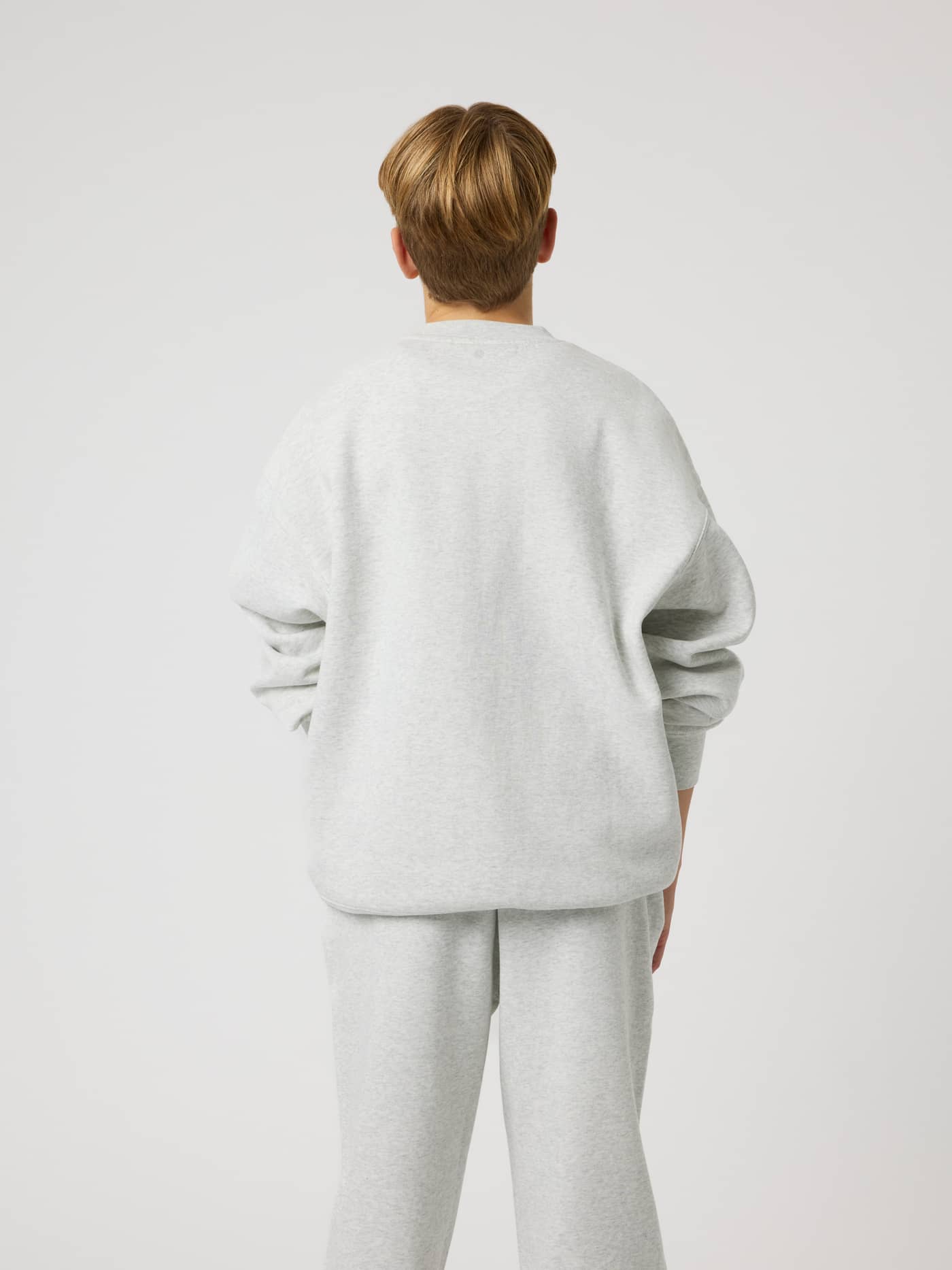 Back view of a kid in the Borg Oversized Sweatshirt, Ultra Light Grey Melange (Grey), with a tennis ball print for kids. - Image 2