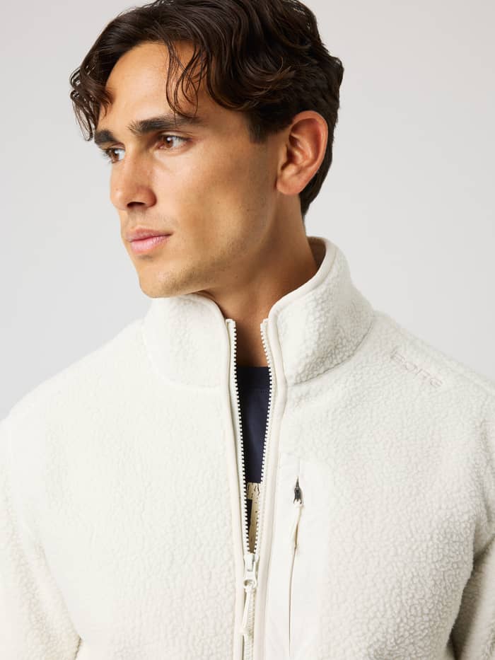 Close-up of a man wearing the Borg Pile Jacket in Tofu (White) with tonal shoulder embroidery and pile fabric for training. - Image 5