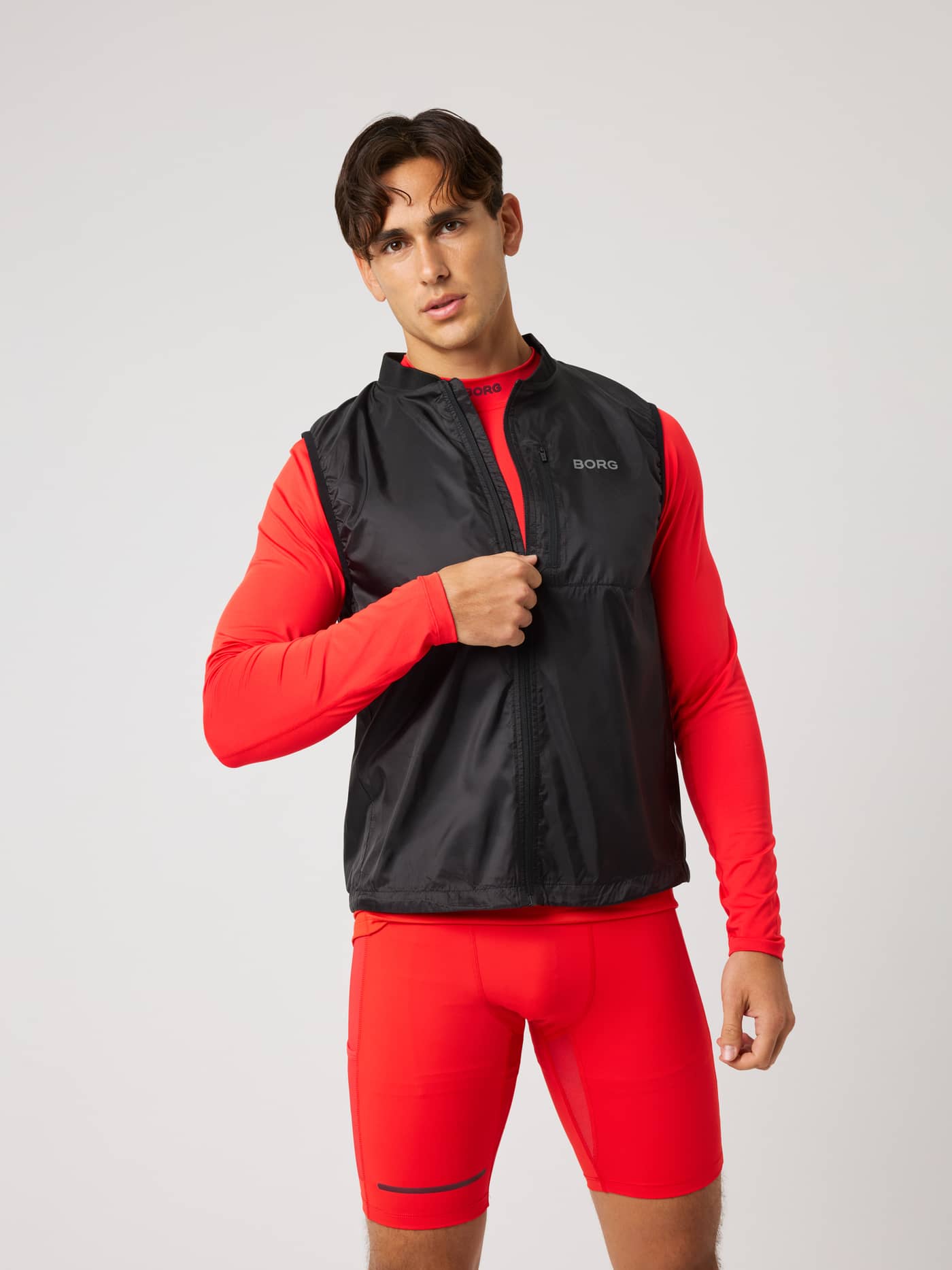 Vue de face d'un homme portant le Borg Performance Vest en Black Beauty (Noir) pour le running avec un logo gris. - Image 1