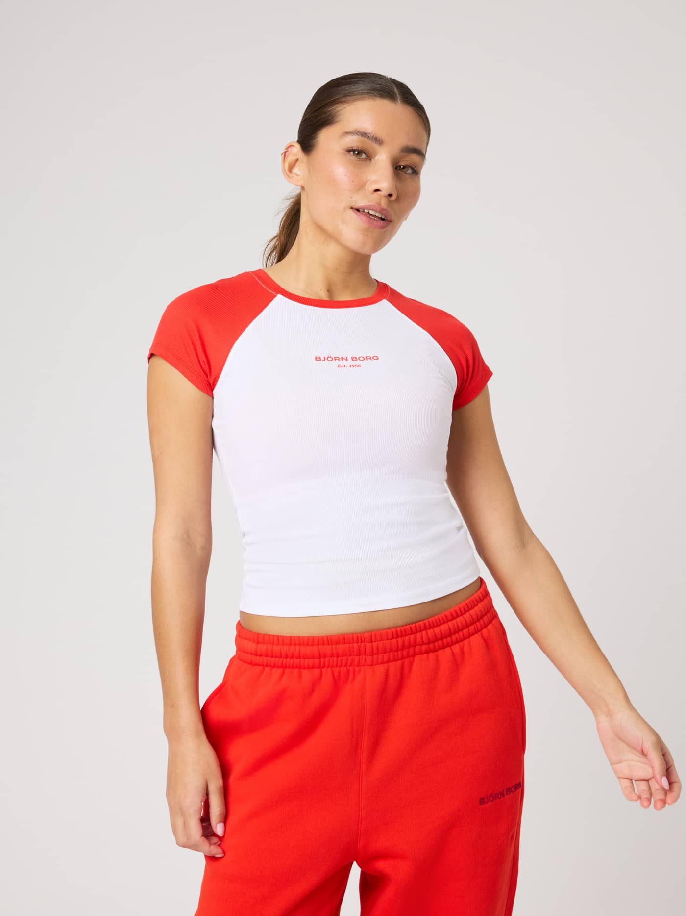 Front view of the Studio Ringer T-Shirt in Brilliant White (White) featuring red raglan sleeves and a red logo print. - Image 3