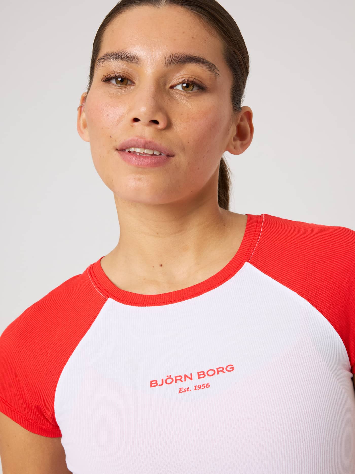 Close-up of the ribbed Studio Ringer T-Shirt in Brilliant White (White) with red raglan sleeves and a red logo for tennis. - Image 7