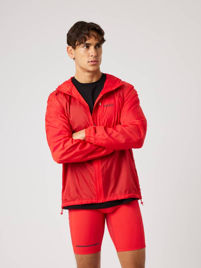 Front view of a man wearing the Borg Performance Wind Jacket in Flame Scarlet (Red) for running and active training.