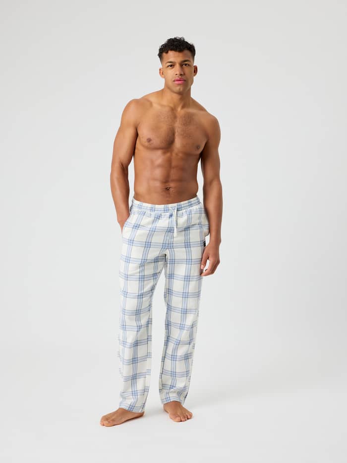 Male model wearing Core Flannel Pyjama Pants in navy tartan pattern with an elastic drawstring waist.