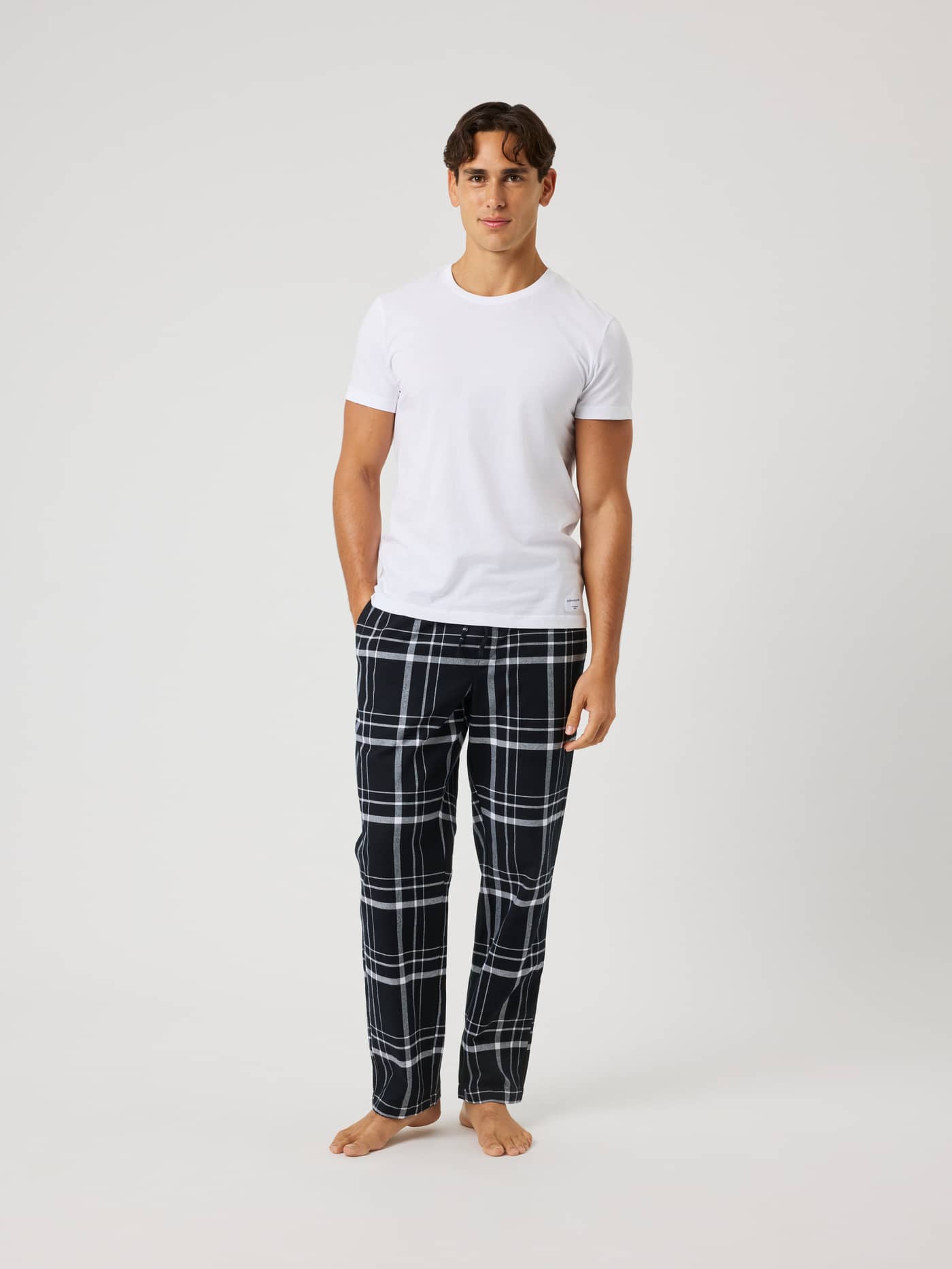 Full-body front view of a model wearing Björn Borg Core Flannel Pyjama Pants in a black, grey and white check pattern. - Image 3