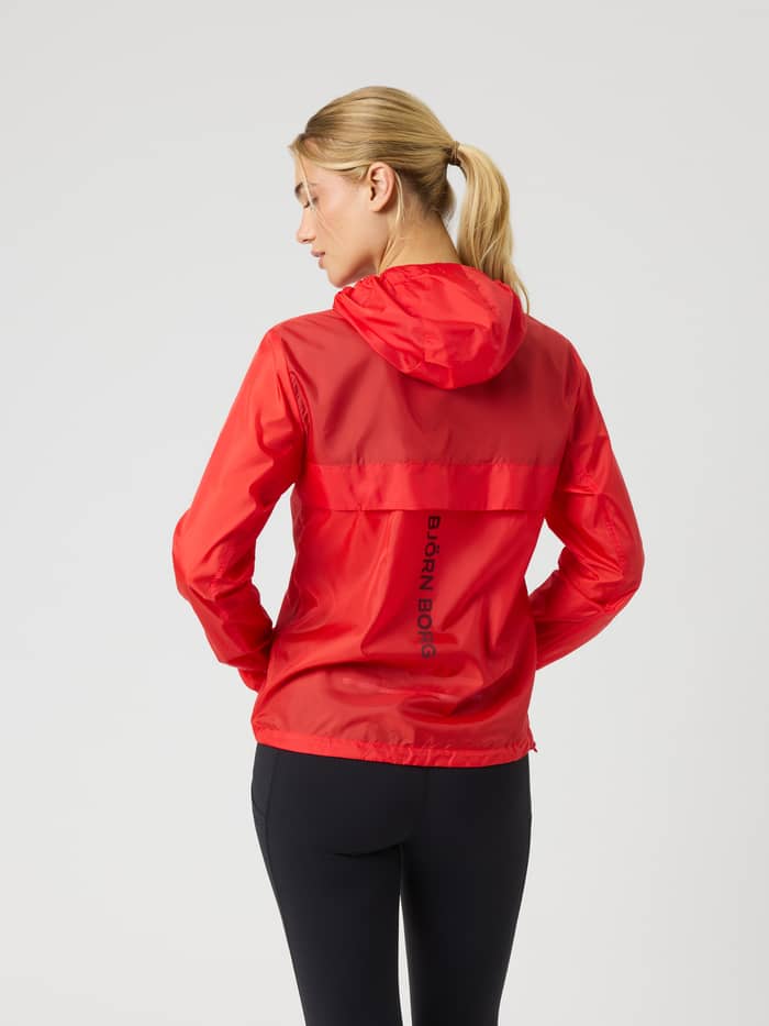 Back view of a model wearing the Borg Performance Wind Jacket in Flame Scarlet (Red) for running with a vertical black logo. - Image 3