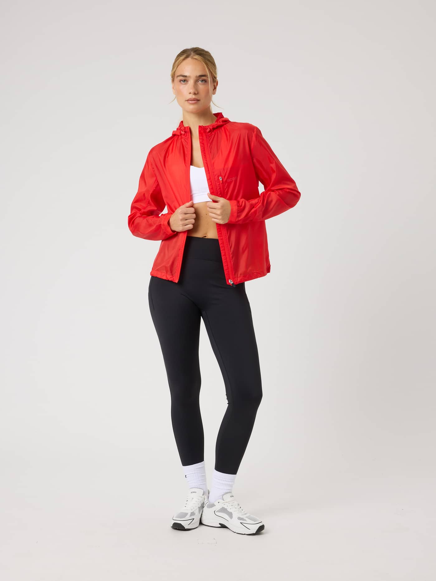 Vista frontal completa de una modelo con la Borg Performance Wind Jacket en Flame Scarlet (Rojo) para running. - Image 1