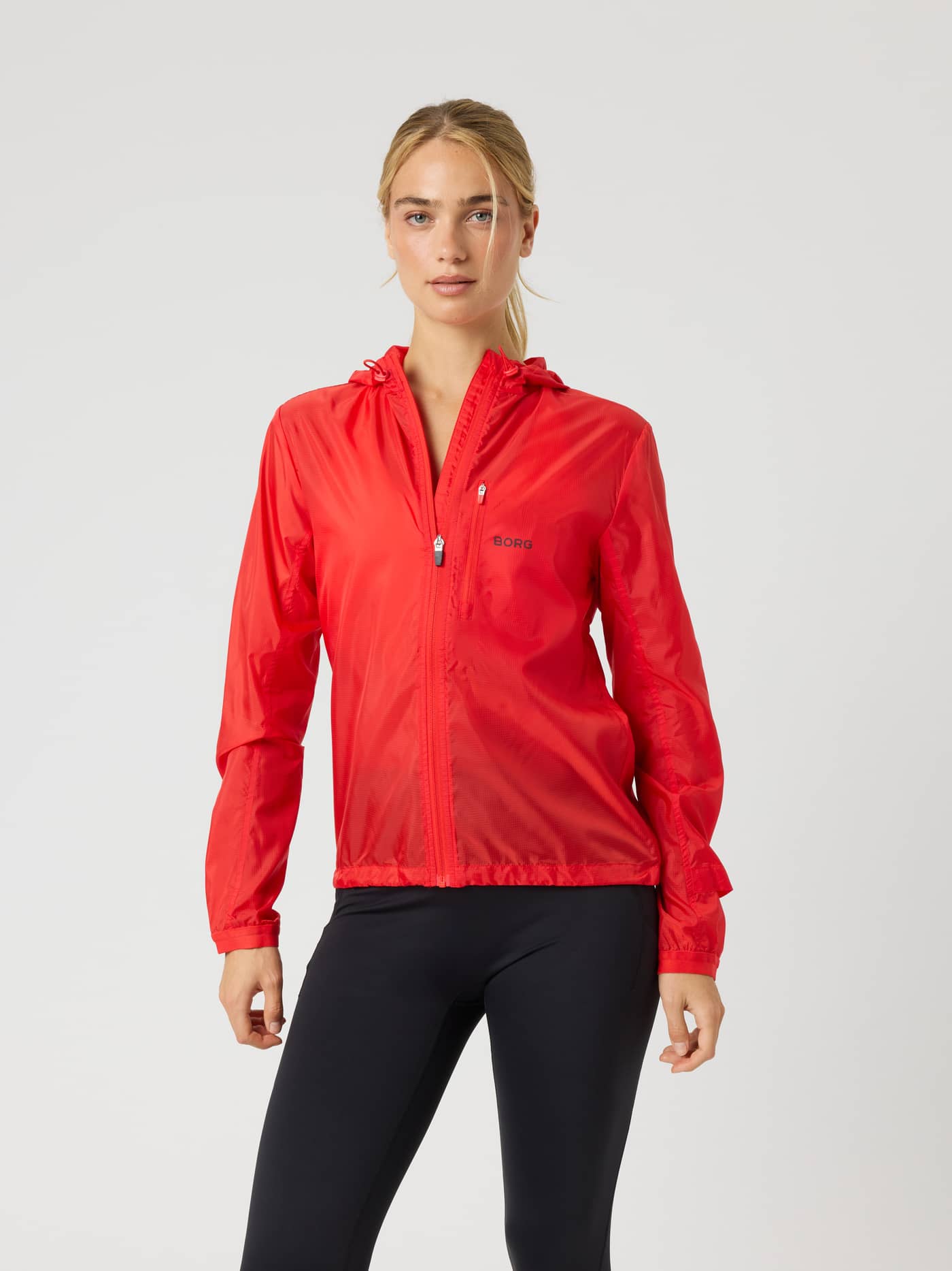 Front view of a woman in the hooded Borg Performance Wind Jacket in Flame Scarlet (Red) with a black logo for running. - Image 2
