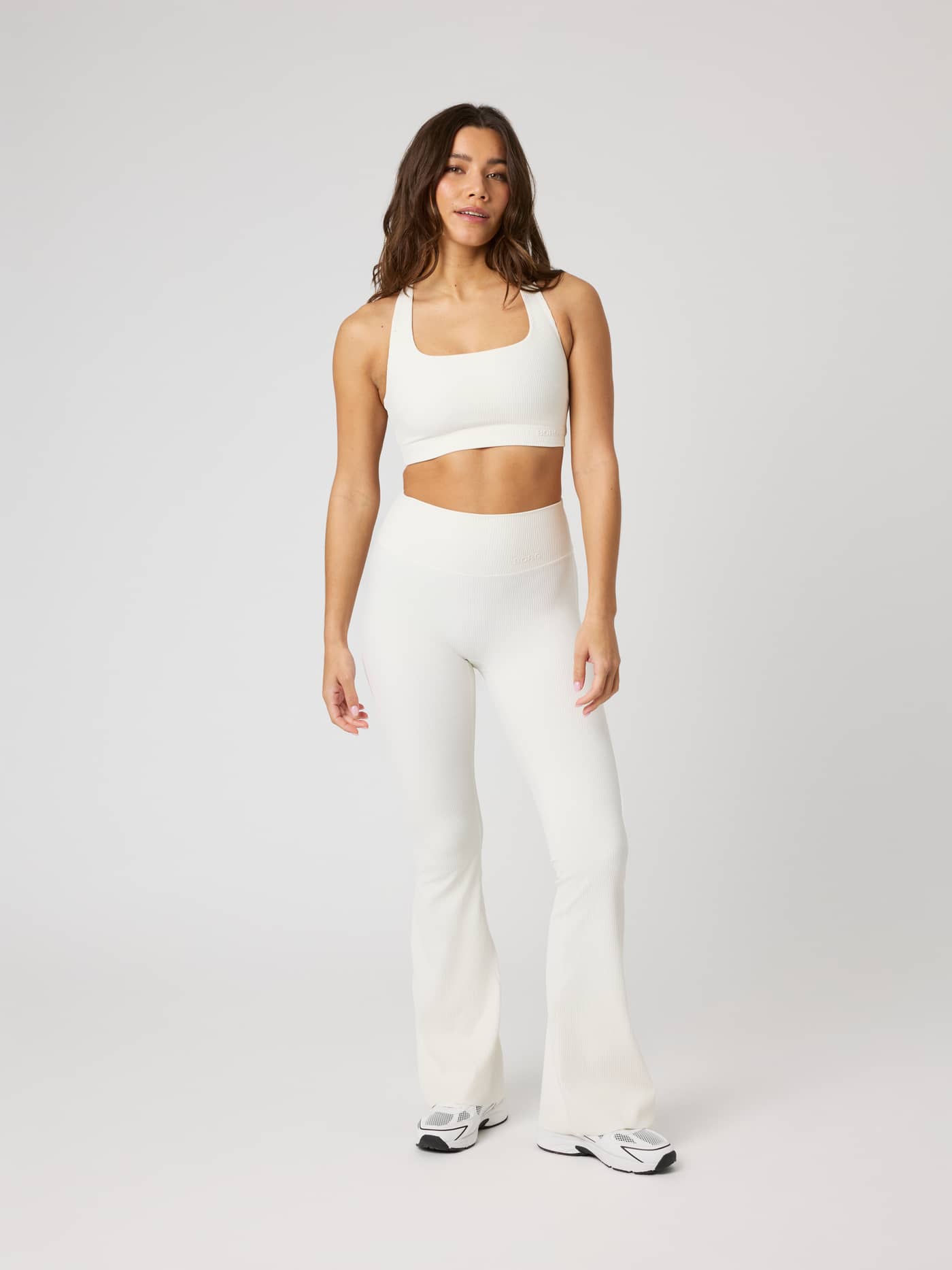 Full-body front view of a model wearing the Studio Ribbed Racerback Bra in Tofu (White) for premium training. - Image 4