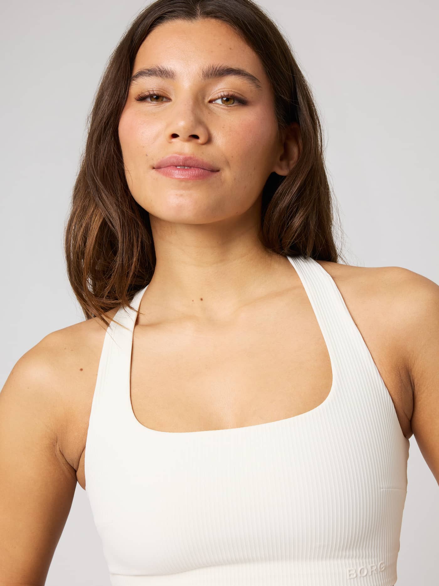Close-up of the Studio Ribbed Racerback Bra in White, featuring a technical ribbed fabric and BORG logo for training. - Image 7