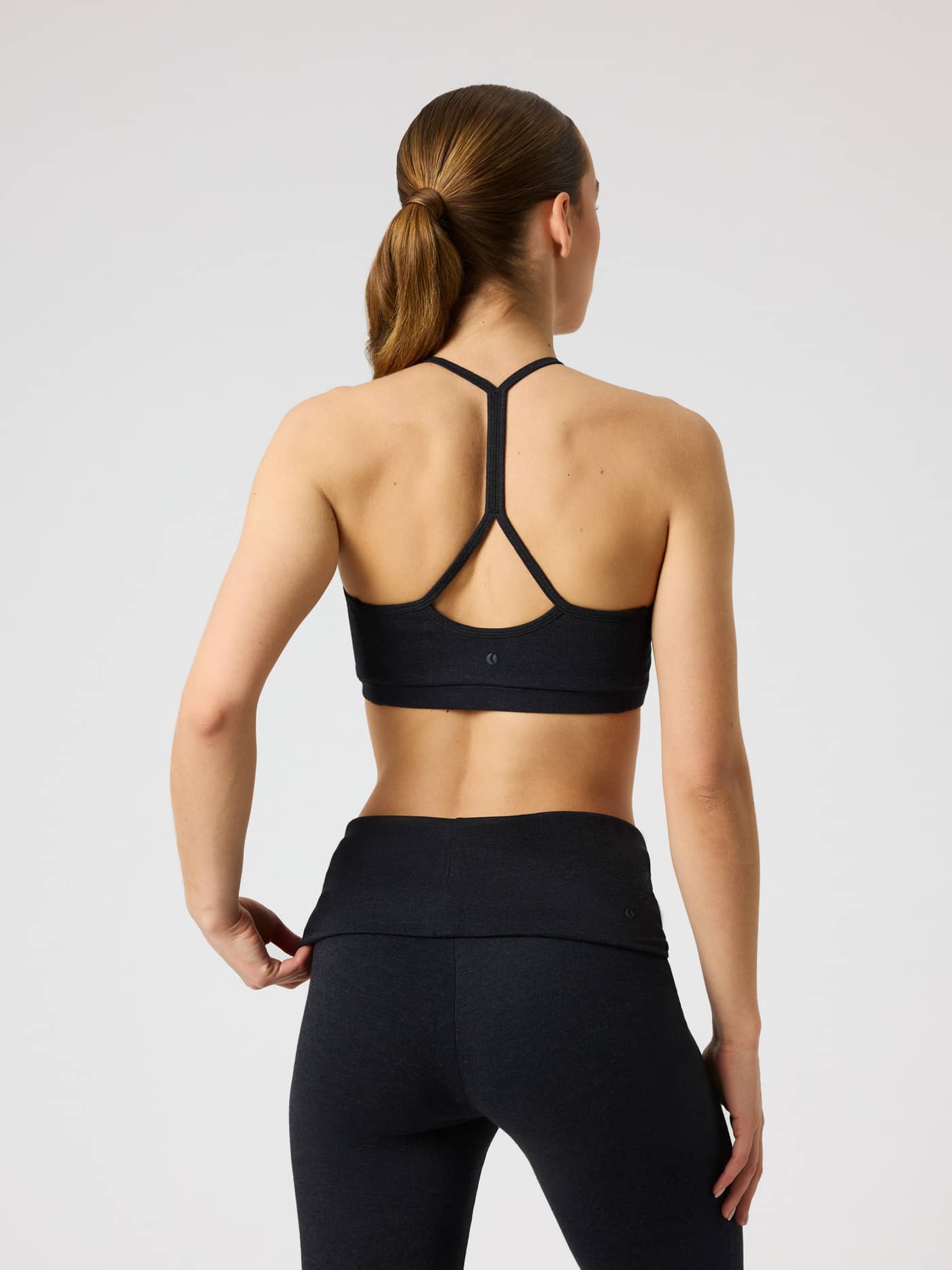 Back view of the Studio Flow Racerback Bra in Black, with a racerback and tonal tennis ball logo for training. - Image 3