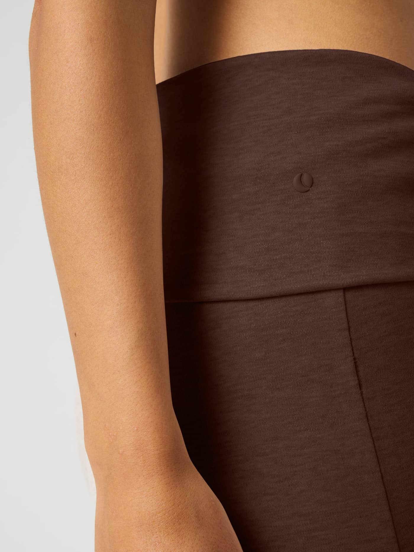 Close-up of Studio Flow Folded Wide Pants in Coffee Bean (Brown) with a foldable waist and tonal tennis logo for training. - Image 4
