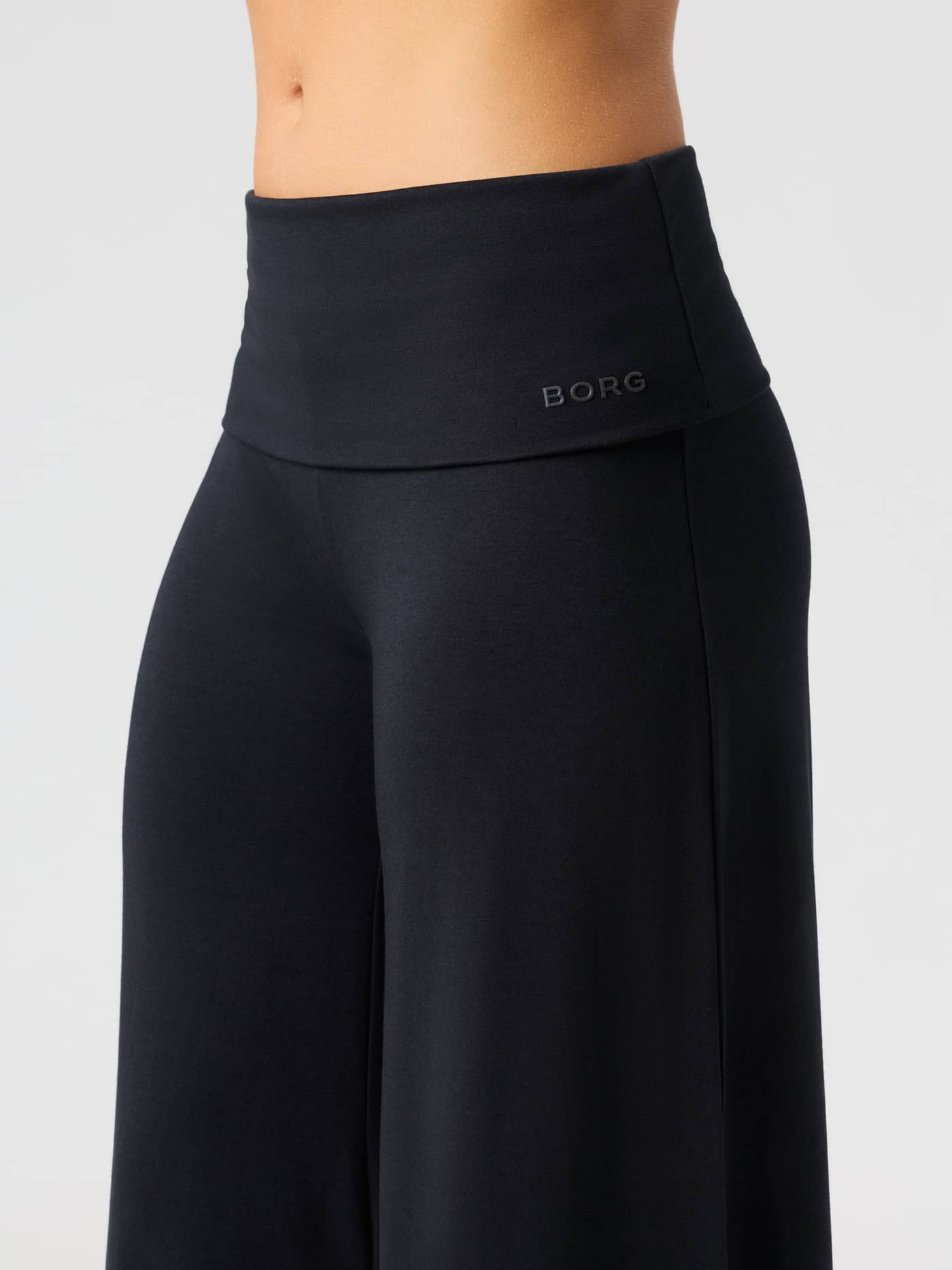 Close-up of the Studio Flow Folded Wide Pants in Black Beauty (Black) featuring the foldable waistband and tonal logo. - Image 5