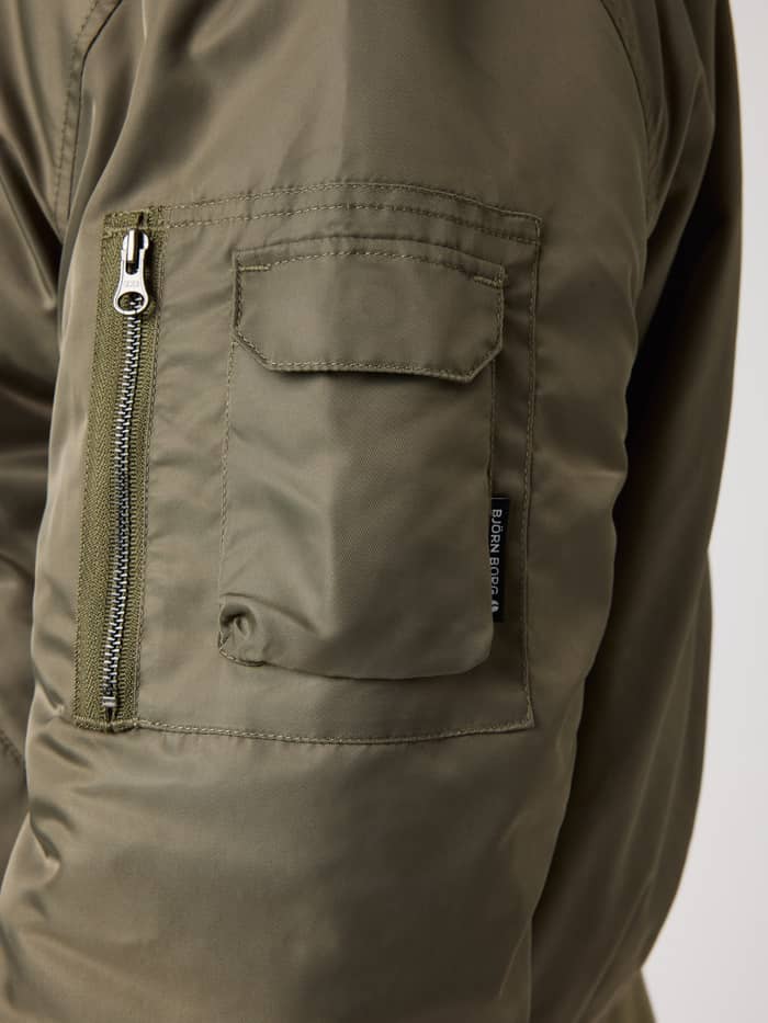 Borg Bomber Jacket in Kalamata (Green) featuring a zippered sleeve pocket with a black logo label detail. - Image 4