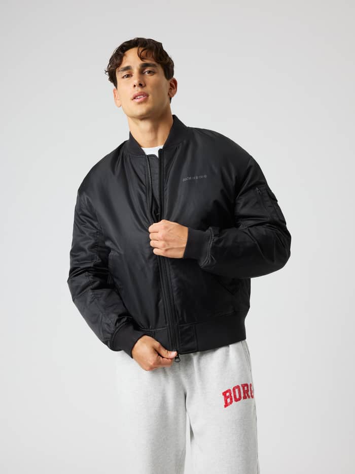 Front view of a man wearing the quilted Borg Bomber Jacket in Black Beauty (Black) for training with a black chest logo.