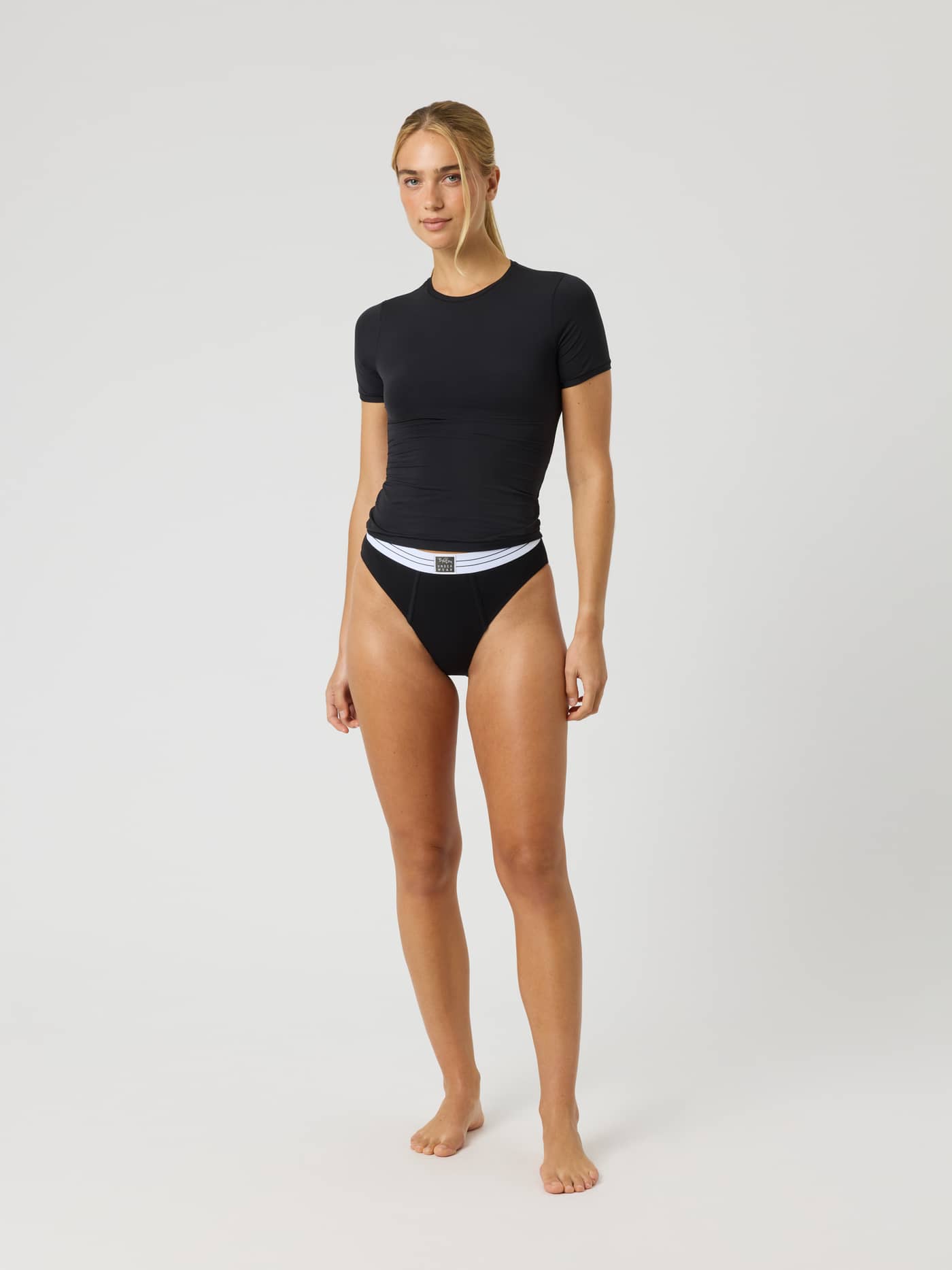 Full-body front view of a woman wearing the slim-fit Comfort T-Shirt in Black, made from soft stretch microfiber. - Image 3