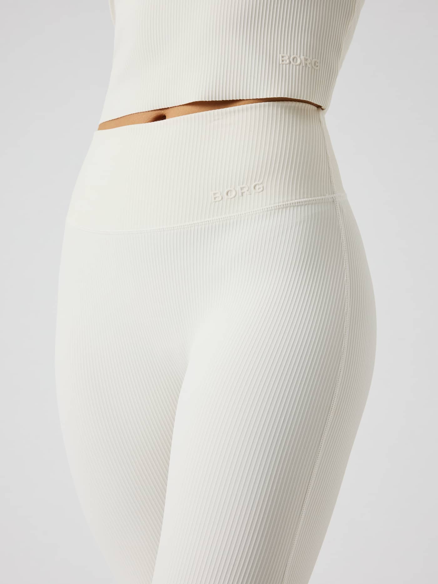 Side view of the Studio Ribbed Flare Tights Tall in Tofu (White) featuring ribbed fabric and a white Borg logo for training. - Image 5