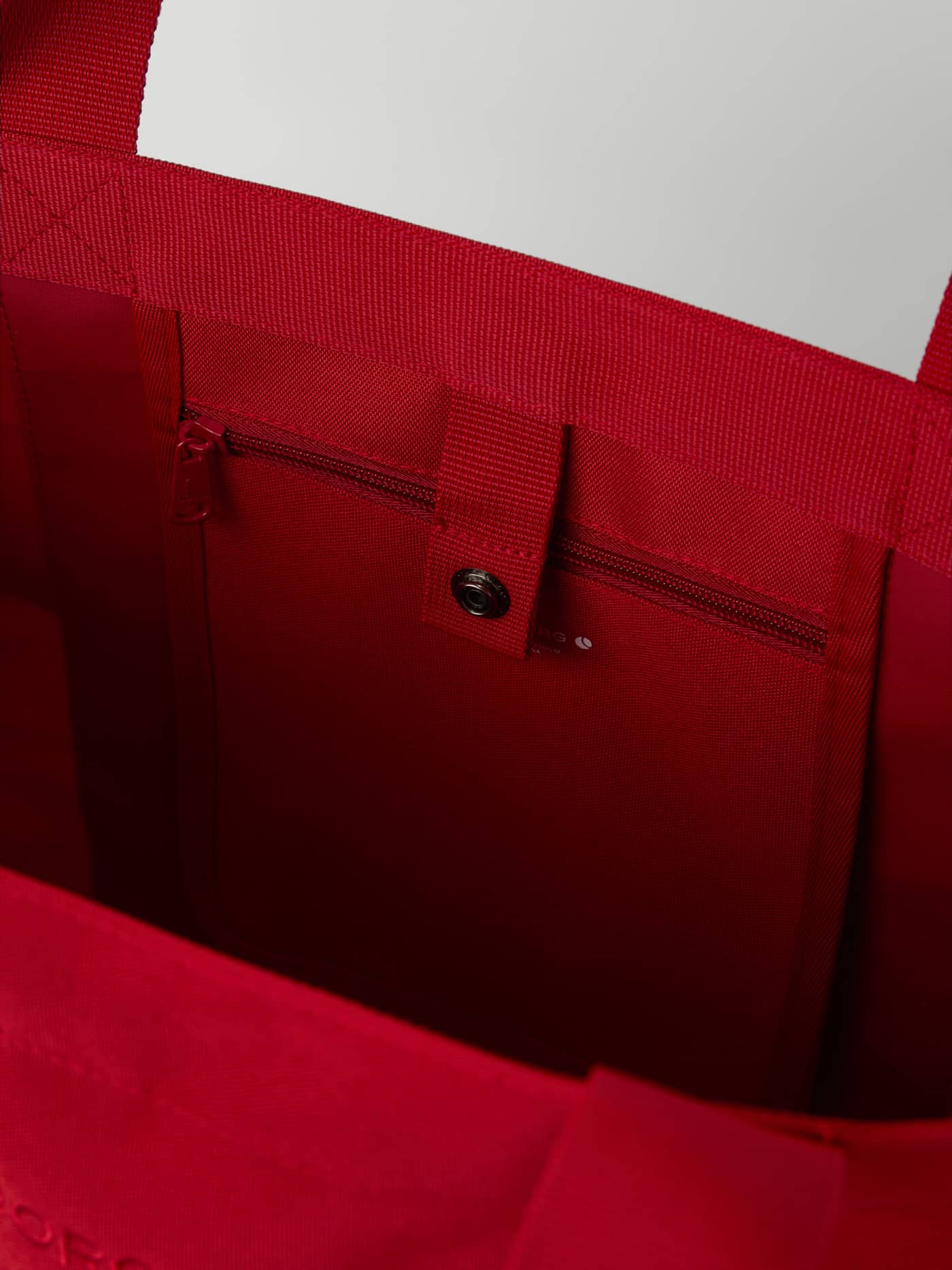 Close-up interior of the Borg Day To Day Tote M - 17L in Samba (Red) with an inside zip pocket and snap button for training. - Image 4