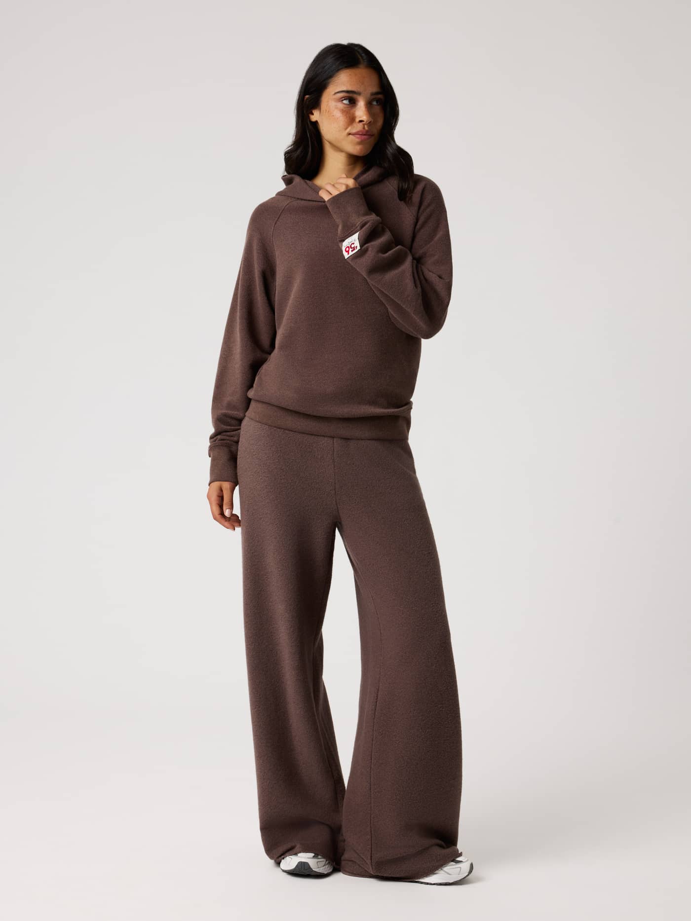 Full-body view of the Studio French Terry Oversized Hoodie in Brown Melange (Brown) with a red logo patch for tennis style. - Image 4
