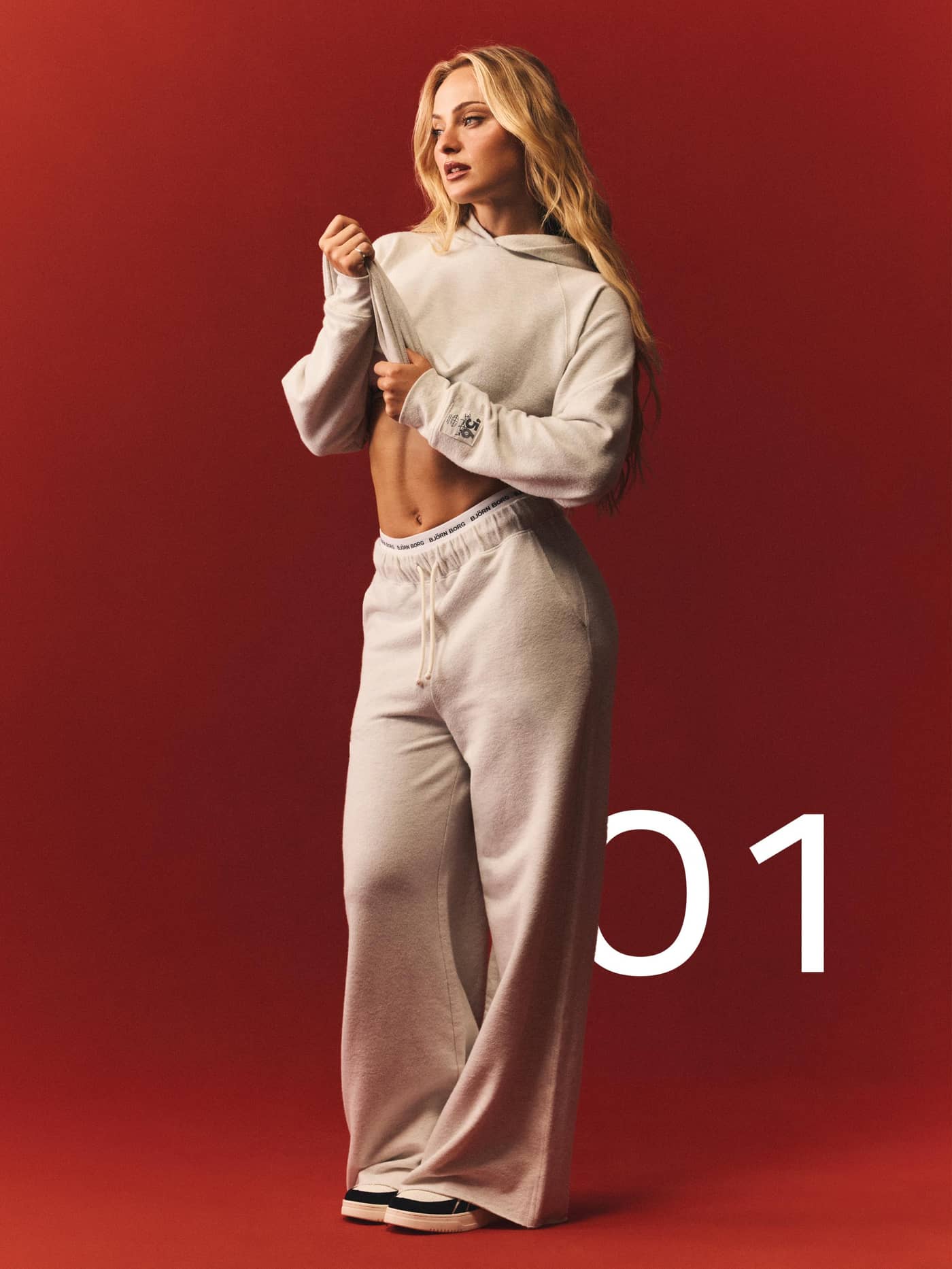 Studio French Terry Oversized Hoodie in Tofu Melange (beige) worn by a model against a red background. - Image 7