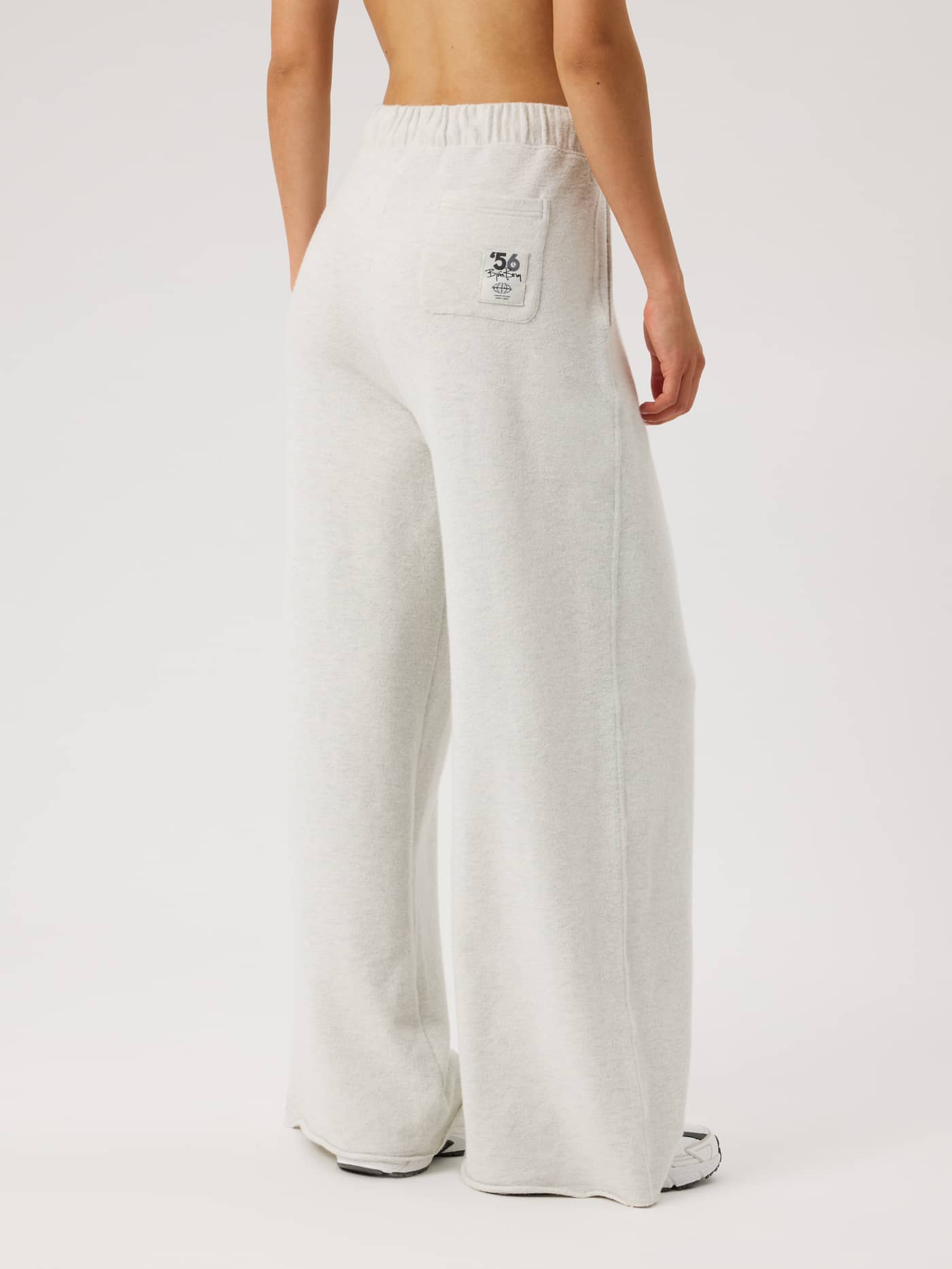 Back view of Studio French Terry Oversized Sweatpants in Tofu Melange (Beige) with a white logo patch on the back pocket. - Image 3