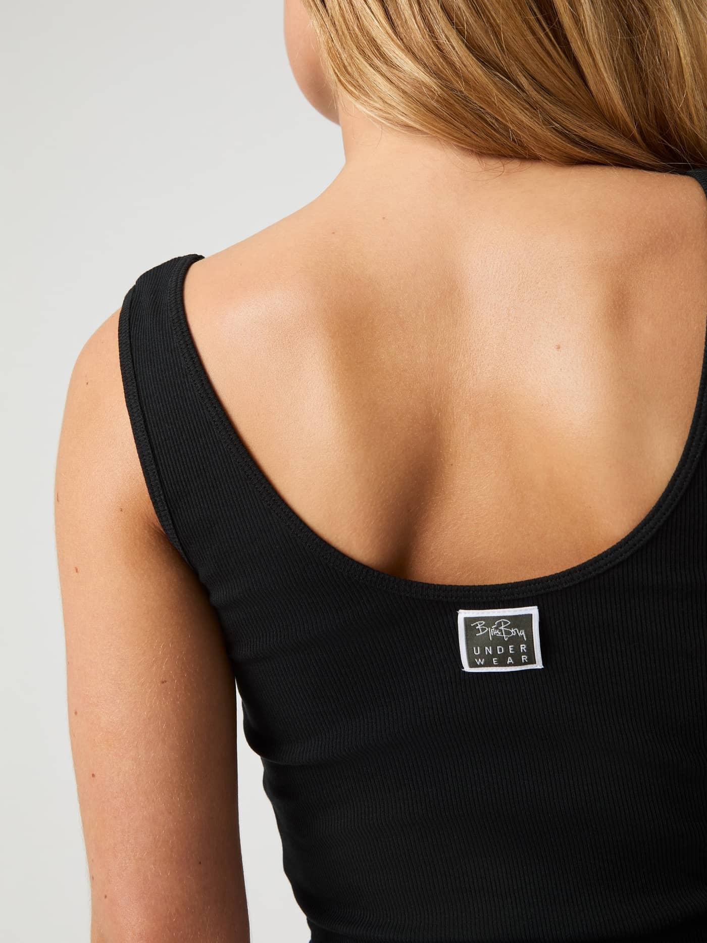 Back view of the Core Original Rib Tank in Black Beauty (Black) with soft ribbed fabric and a white back logo label. - Image 4