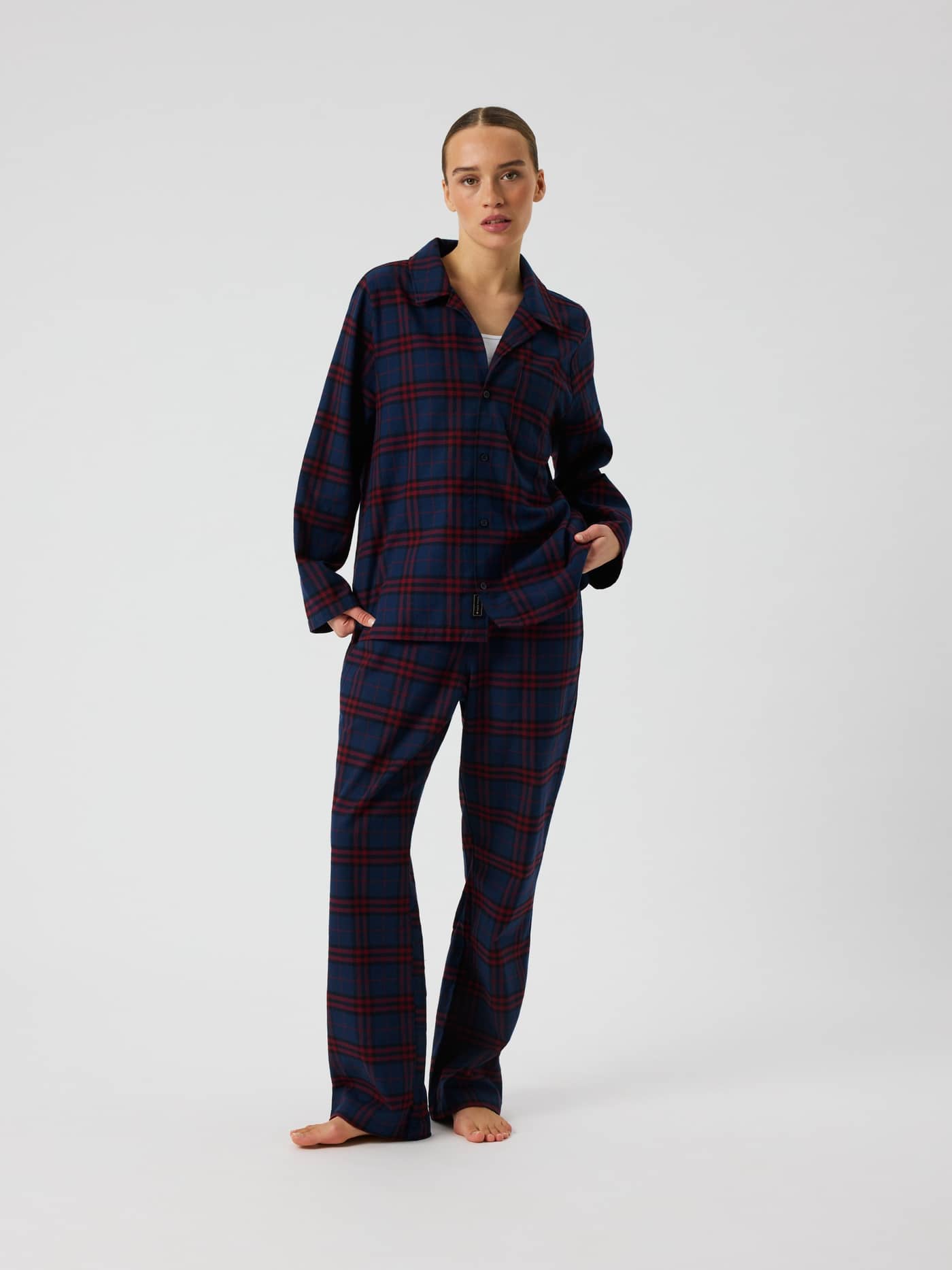 Front view of a model wearing the Core Flannel Pyjama Pants in a blue and red tartan plaid pattern. - Image 1