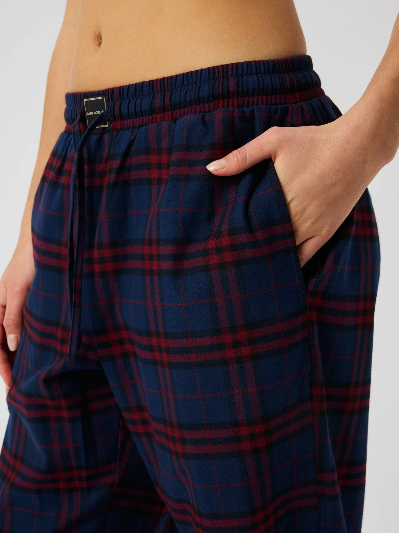 Close-up of the Core Flannel Pyjama Pants featuring a red and blue tartan check pattern and side pocket. - Image 5