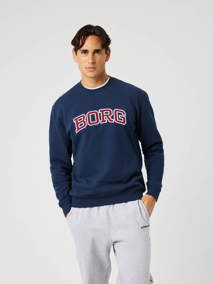 Male model wearing the Borg Classic Print Sweatshirt in Dress Blues (navy) featuring a red and white chest print.