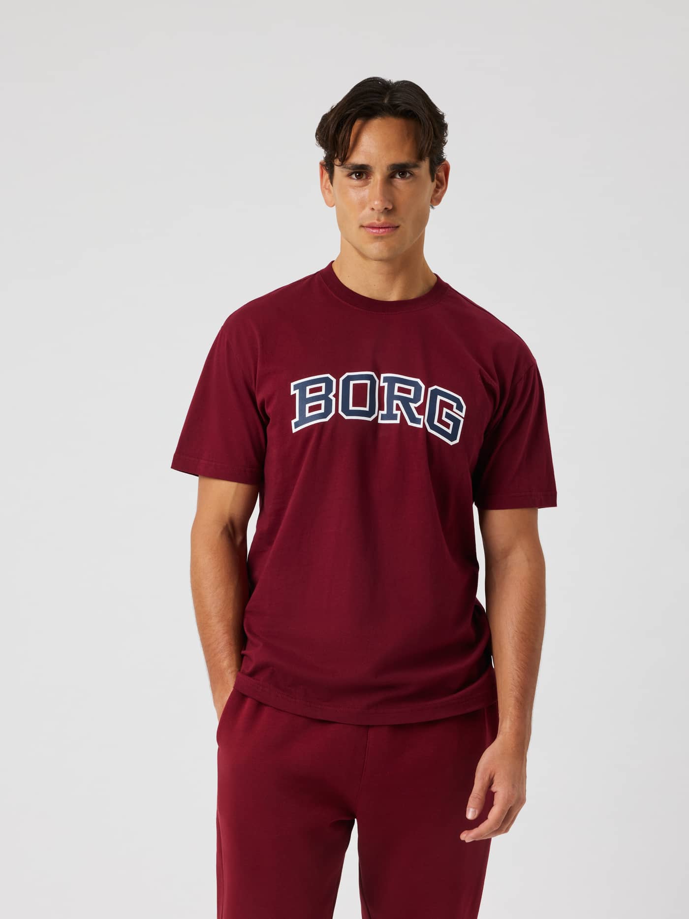 Male model wearing the Borg Classic Print T-Shirt in Cabernet (red) featuring a white and navy BORG logo across the chest. - Image 1