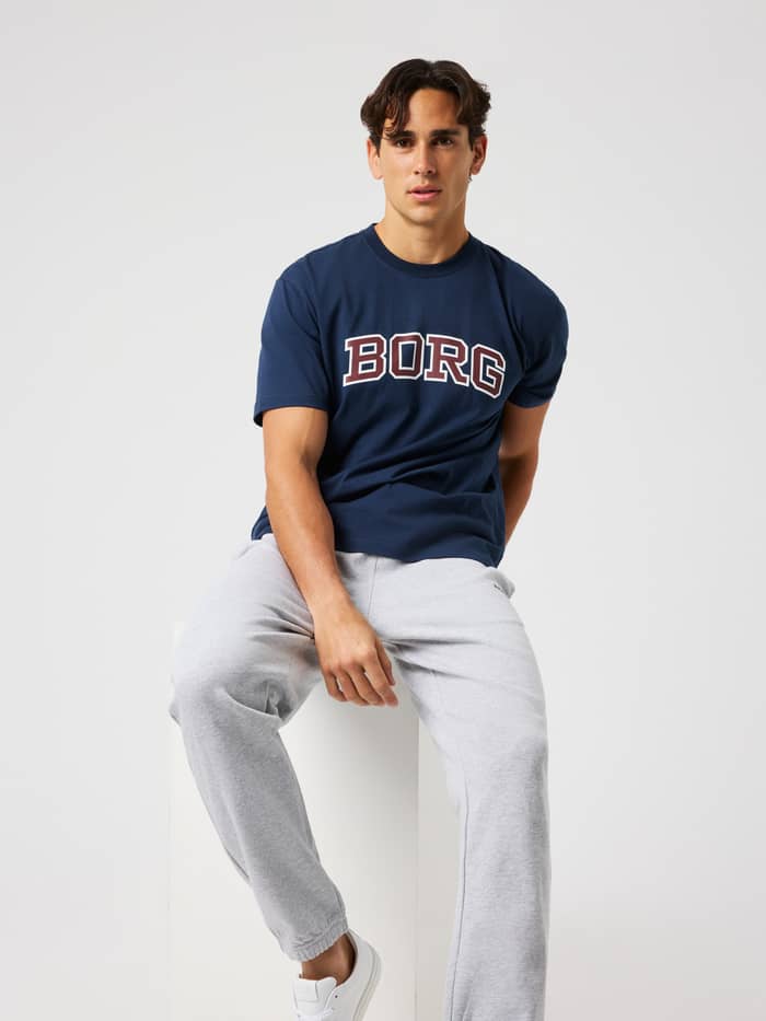Male model sitting down wearing the Borg Classic Print T-Shirt in Dress Blues (Navy) with a BORG print on the chest.