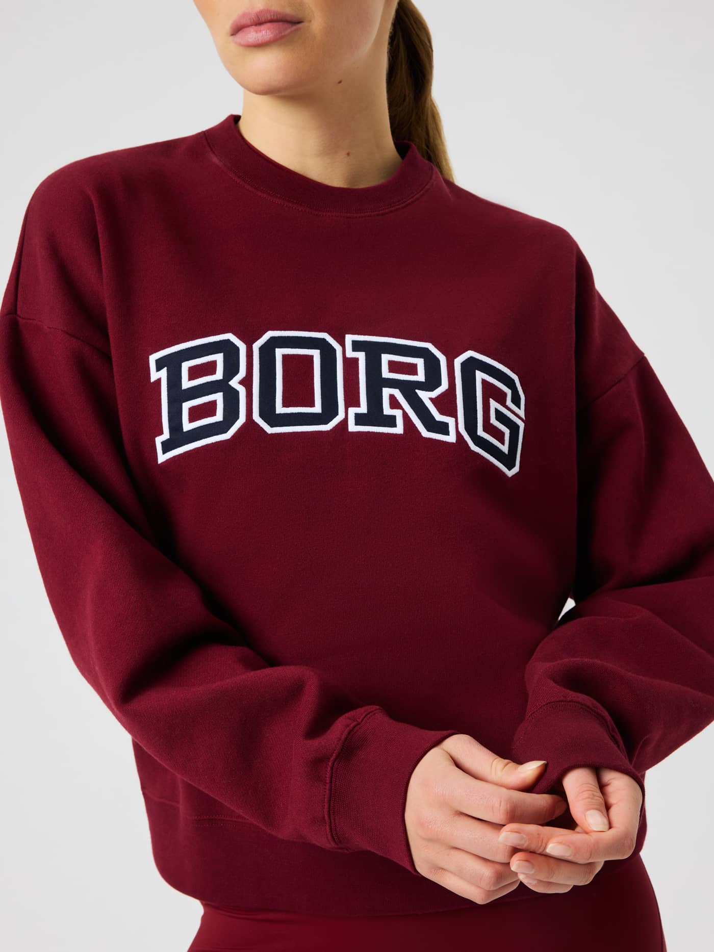 Front view of the Borg Boyfriend Sweatshirt in cabernet (red) with a large arched white and dark navy logo across the chest. - Image 1