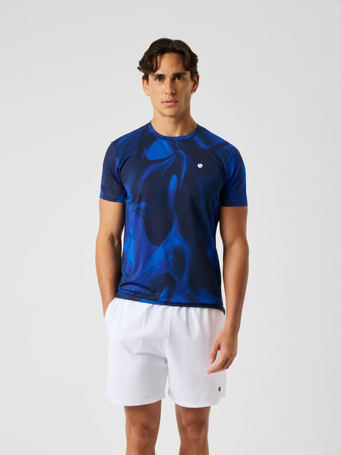 Man wearing the Ace Printed T-Shirt in blue and dark blue wave print, featuring a white logo for tennis.