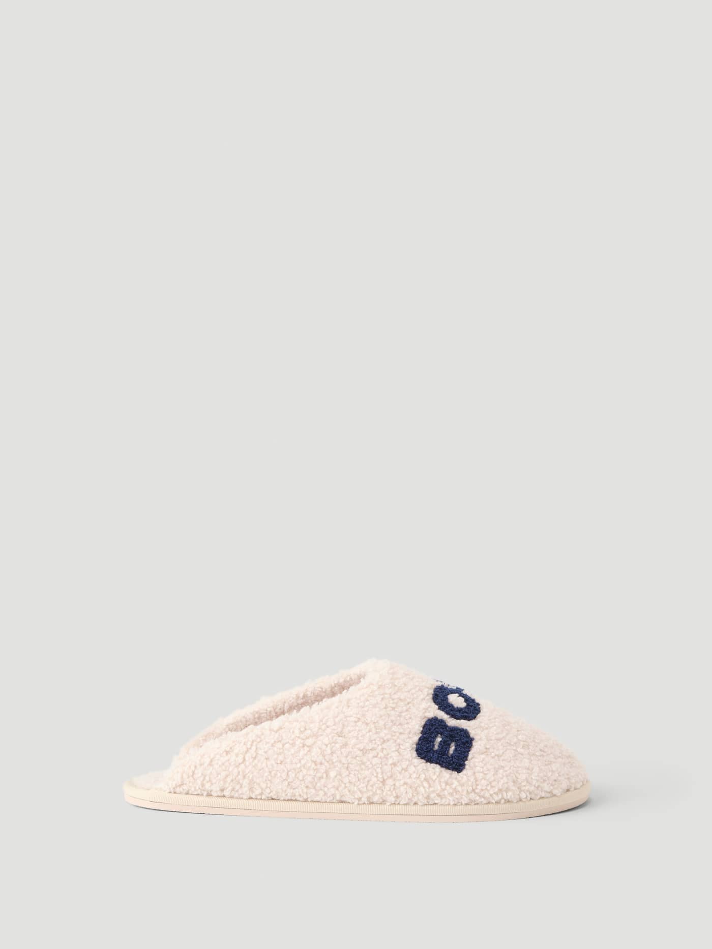 Side view of the Haven Slipper in Tofu and Peacoat, featuring soft polyester pile and navy Borg branding on the vamp. - Image 3