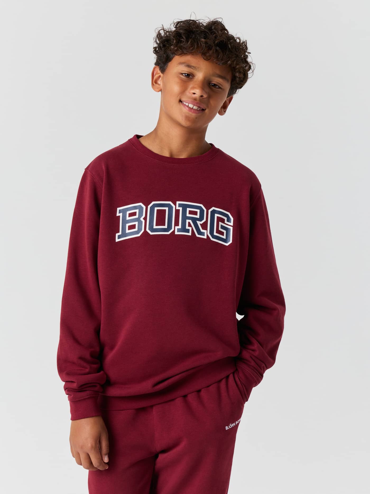 Front view of a young boy wearing the Borg Classic Print Sweatshirt in Cabernet (red). - Image 1