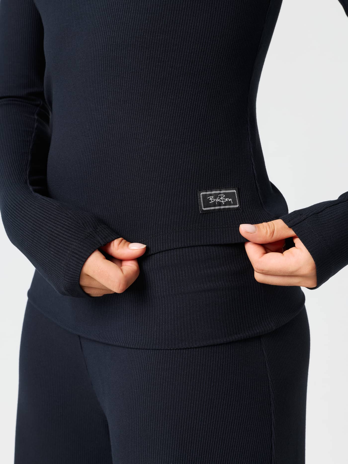 Close-up of the Studio Rib Long Sleeve in Black Beauty (Black), highlighting the ribbed texture and logo label. - Image 4