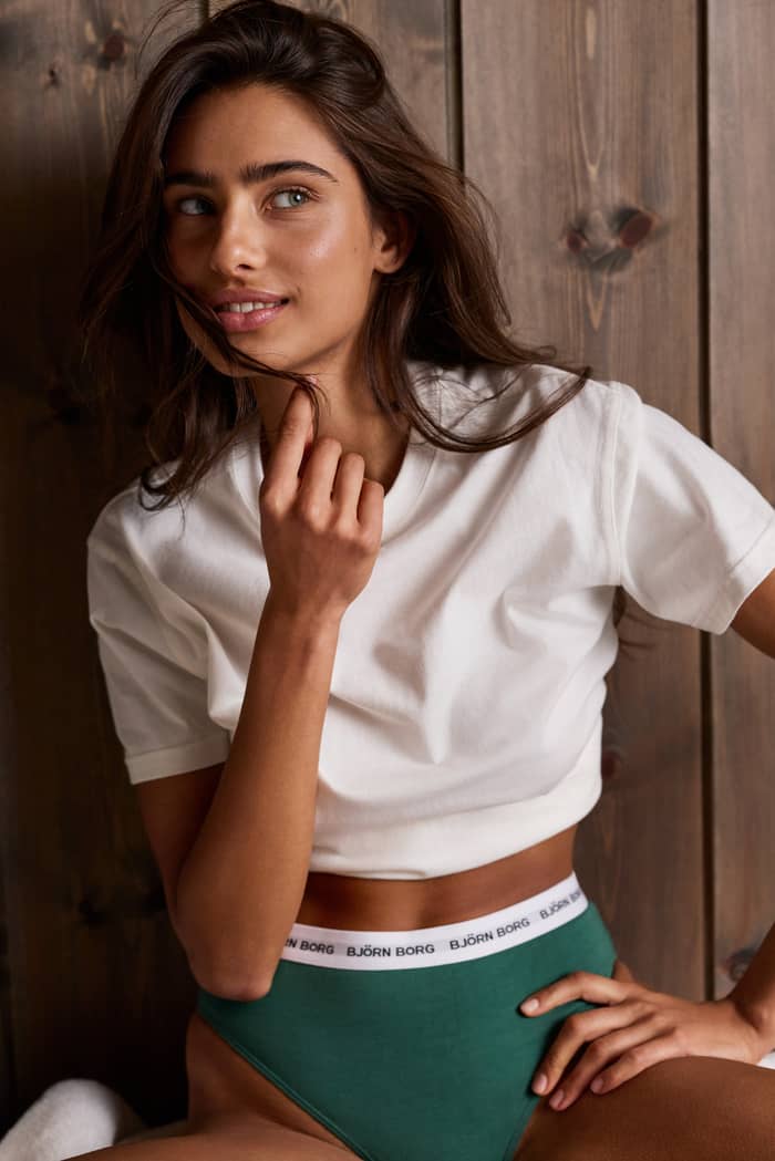 Close-up van een vrouw in de Logo Highwaist Briefs 3-pack, met groene slips en een witte elastische logotailleband.