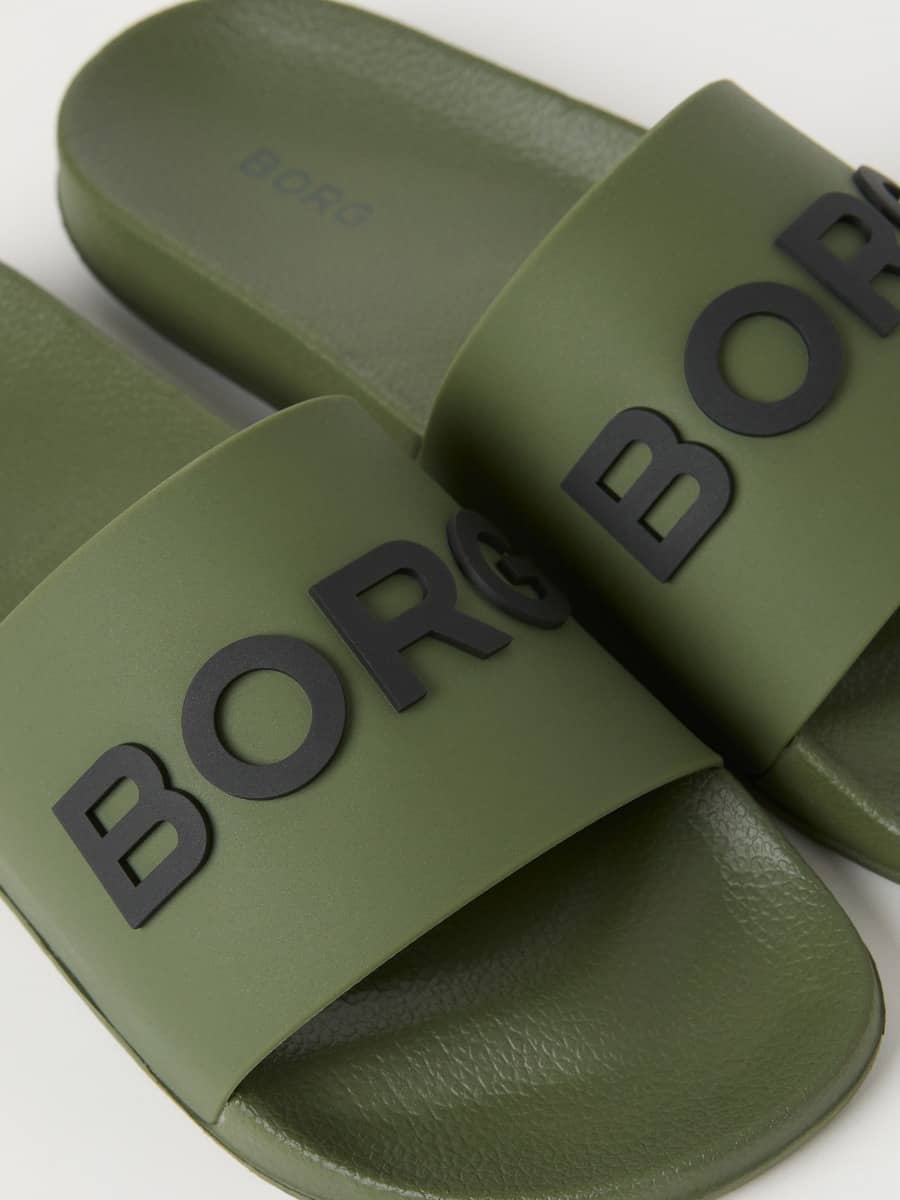 Detailed close-up of green Björn Borg KNOX pool slides for men, featuring a bold black BORG logo on the durable strap. - Image 2