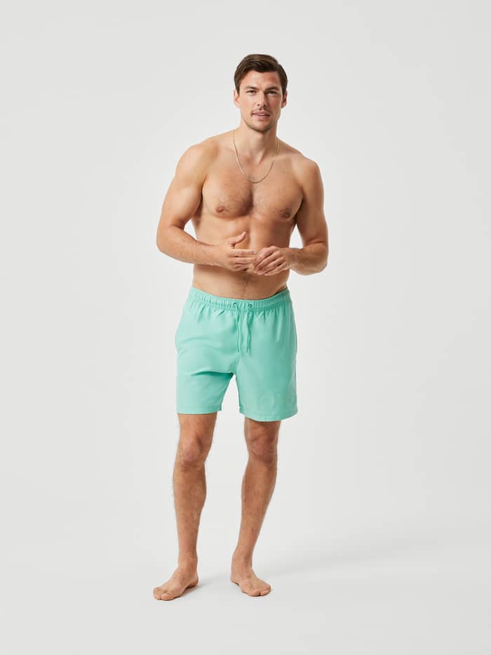 Full-body front view of a man wearing Neptune Green (Green) Borg Swim Shorts in a quick-drying recycled material.