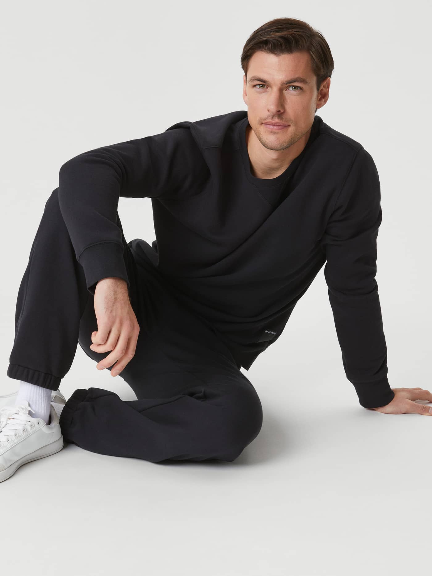 Front view of a man sitting in the stylish Björn Borg Centre Crew in Black Beauty (Black) for versatile everyday wear. - Image 1