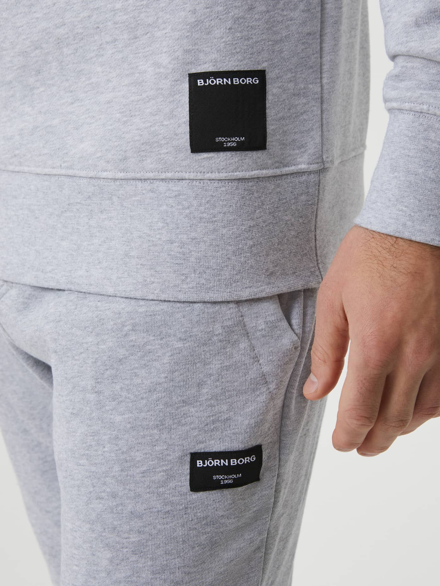 Close-up of the iconic black woven logo label on the men's Centre Crew in Light Grey Melange (Grey), showcasing quality. - Image 5